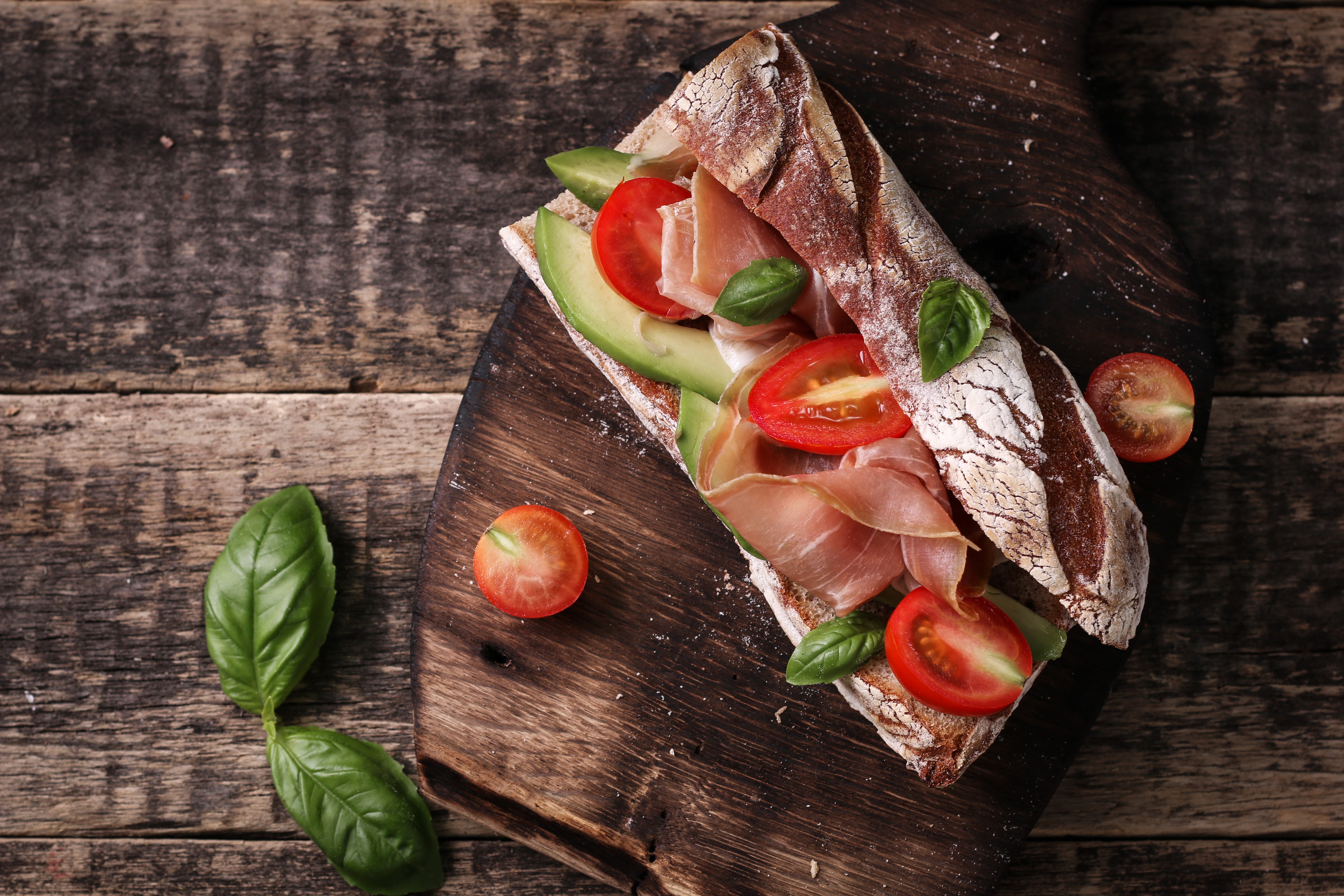 Sandwich with ham, avocado, and tomatoes on a cutting board HD Wallpaper