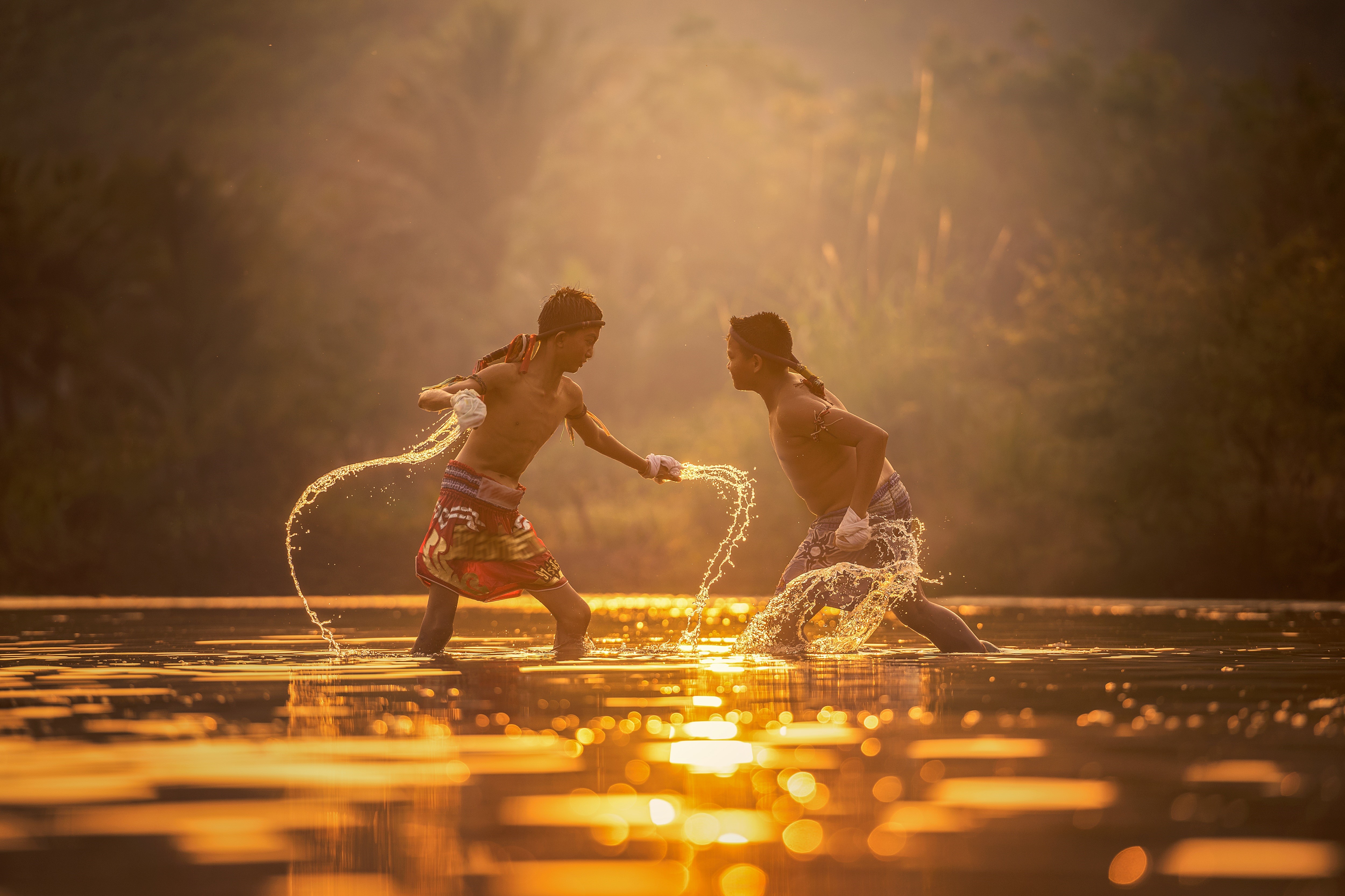 Two boys fighting in water at sunset HD Wallpaper