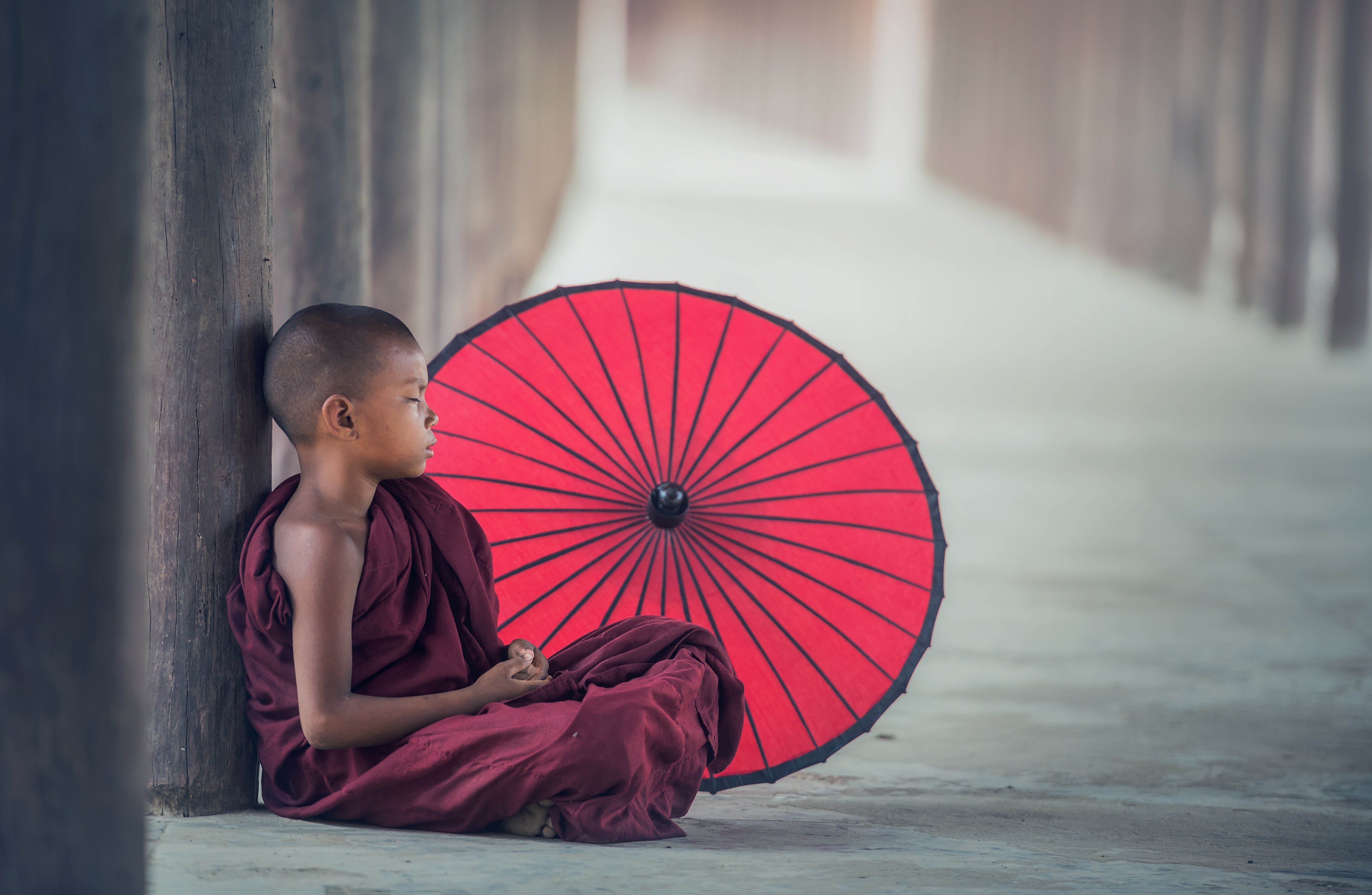 Young monk sitting with red umbrella HD Wallpaper