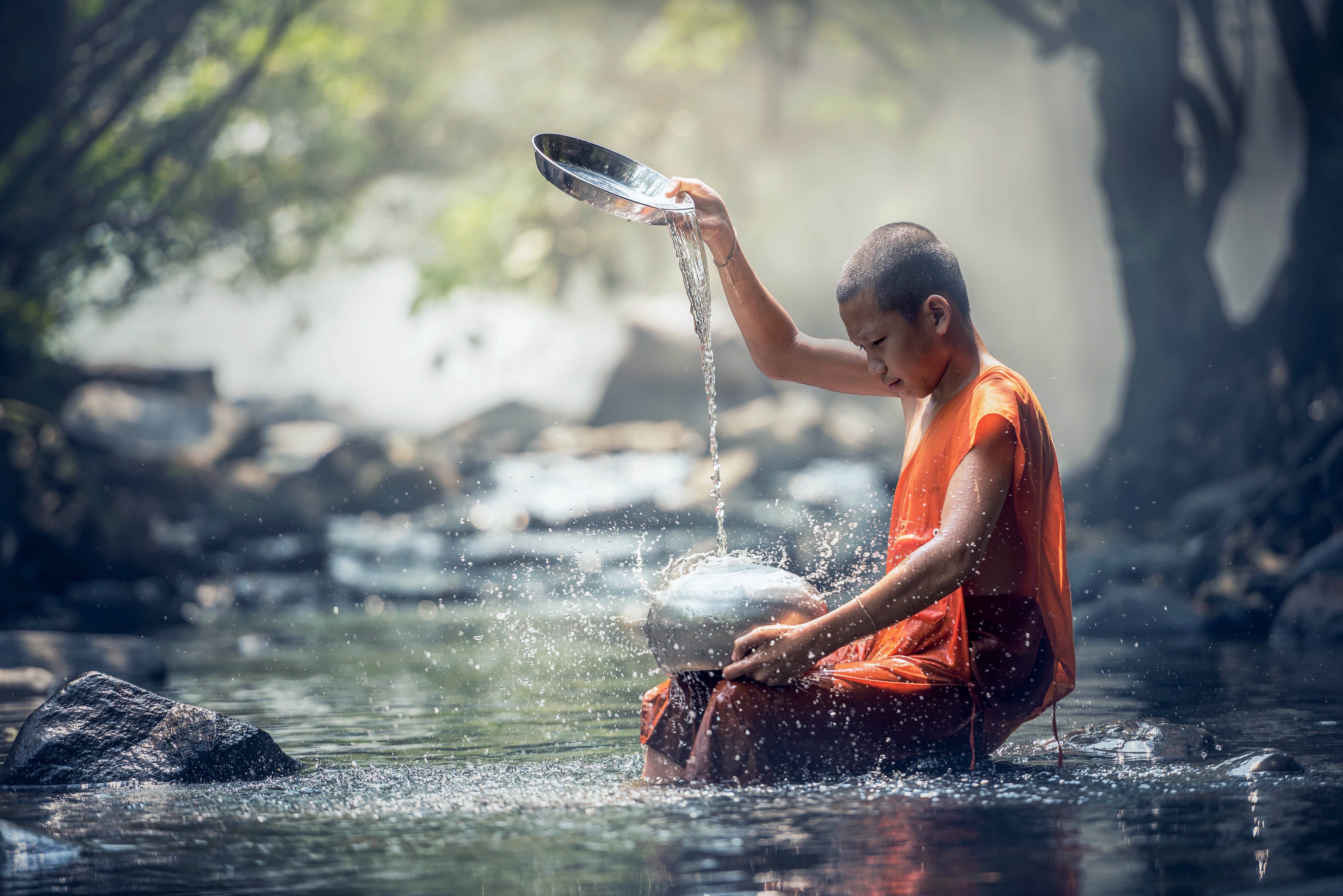 Young monk pouring water in a stream HD Wallpaper