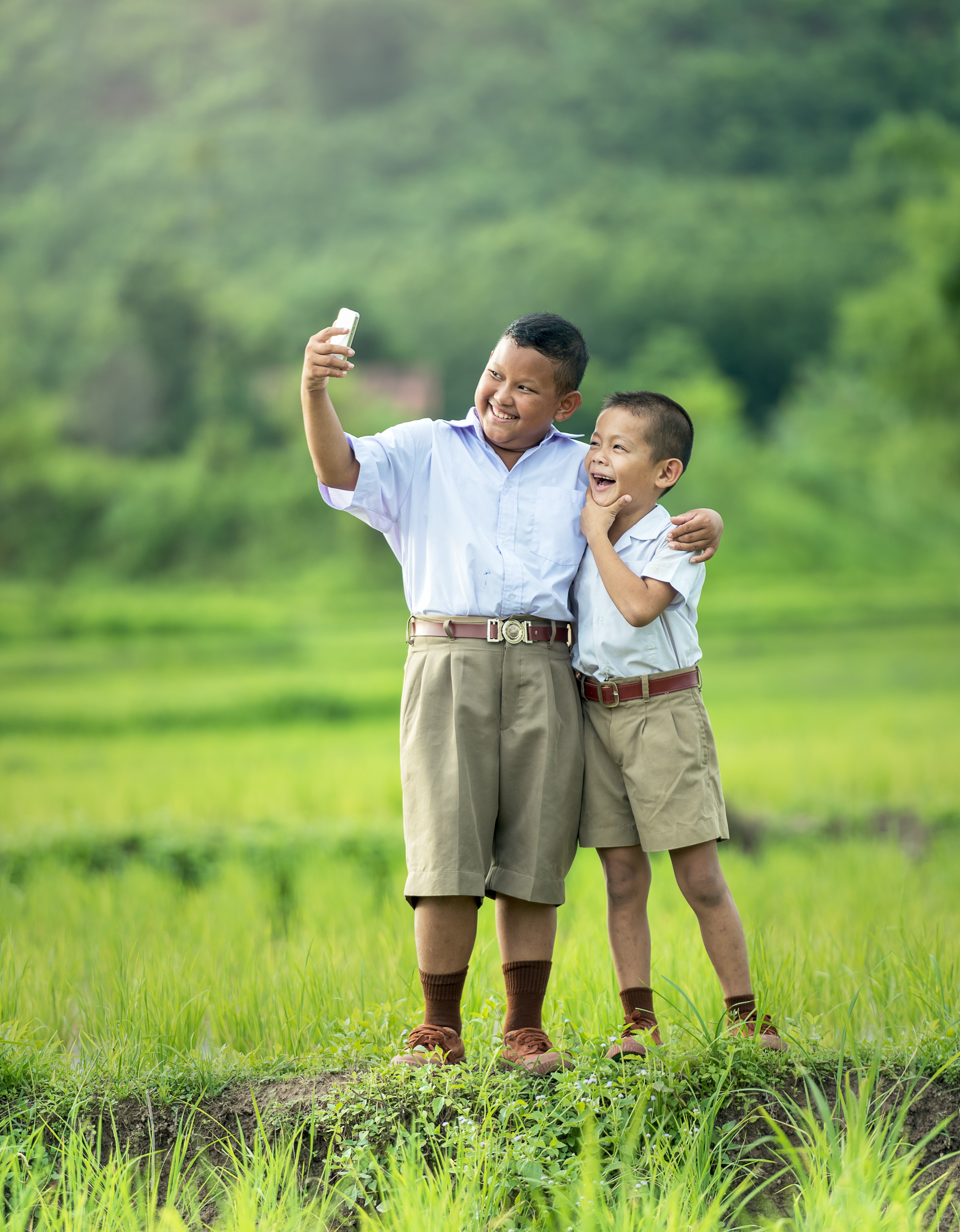 Two Asian schoolboys taking a selfie in a field HD Phone Wallpaper