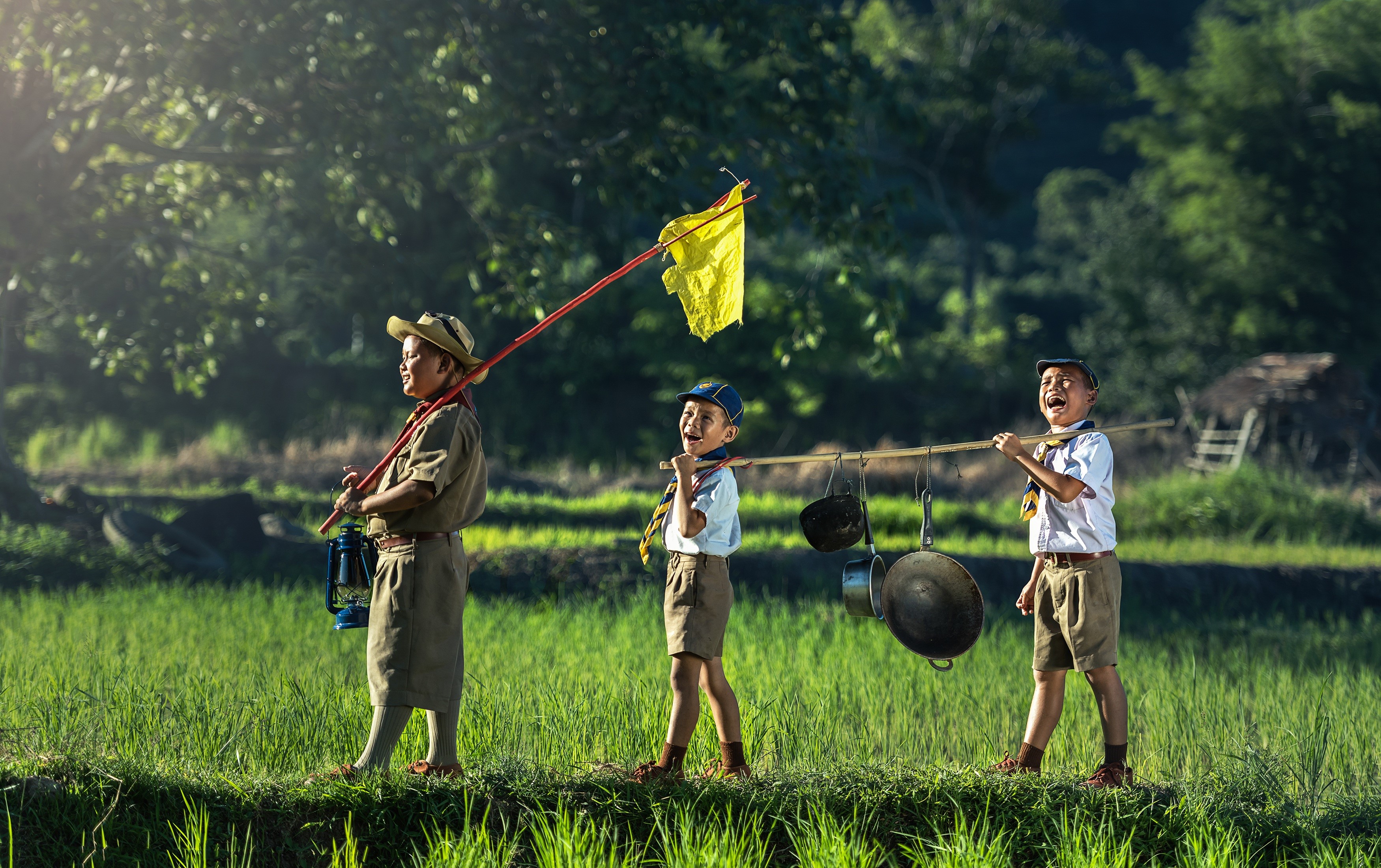 Three boys in scout uniforms walking through a field HD Wallpaper