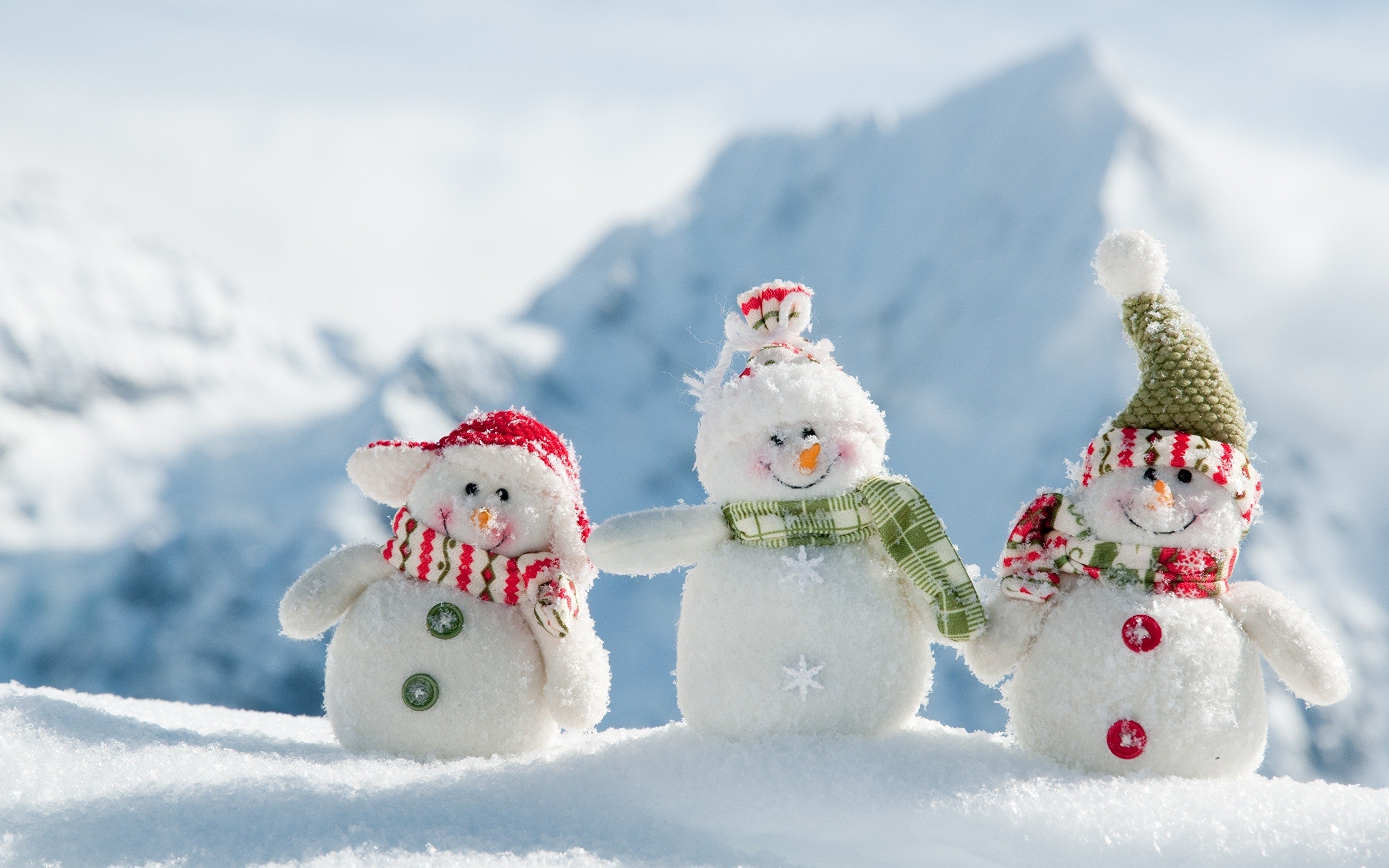 Three snowmen in the snow with mountains in the background HD Wallpaper
