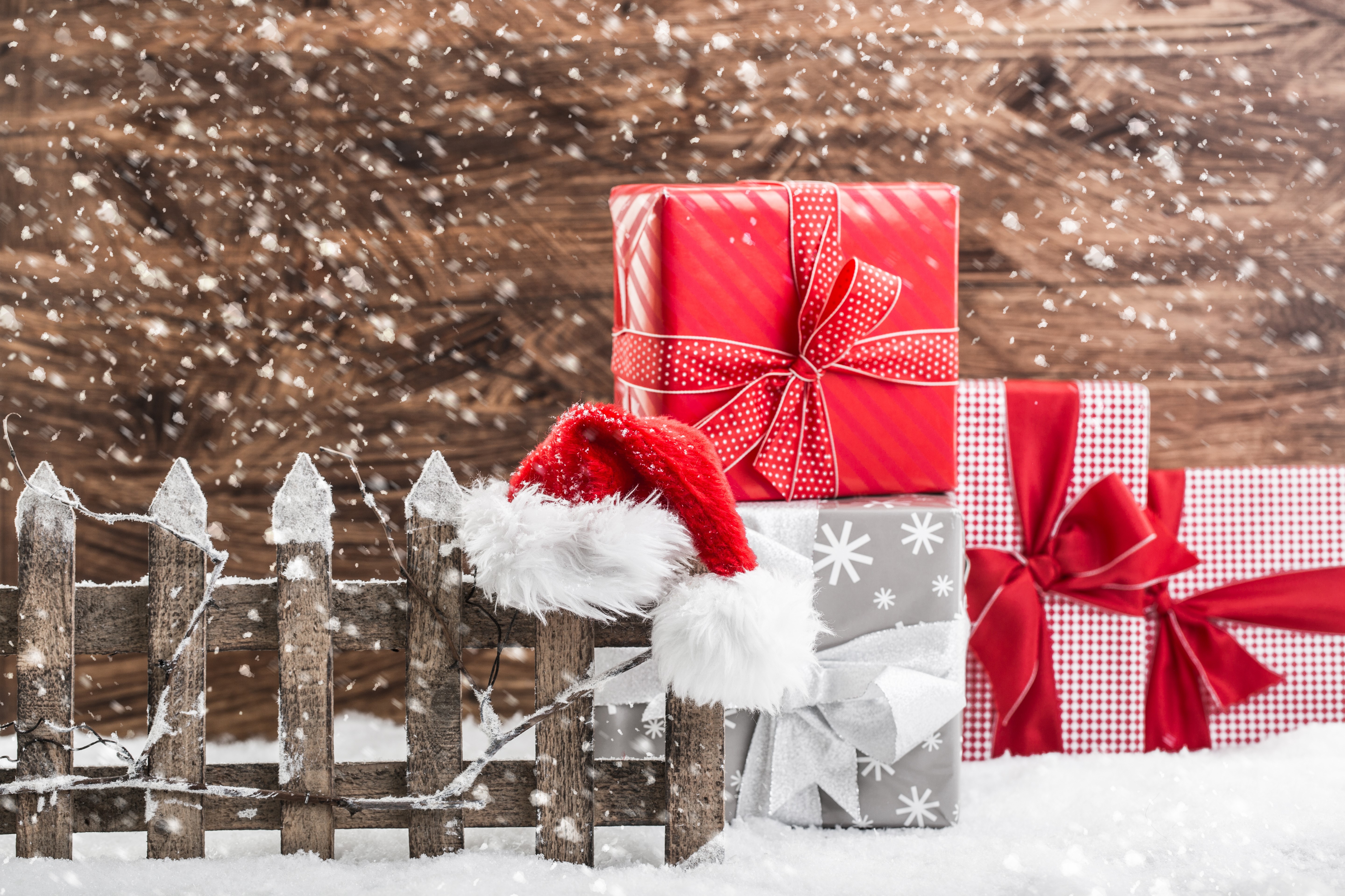 Christmas gifts and Santa hat on a snowy fence HD Wallpaper