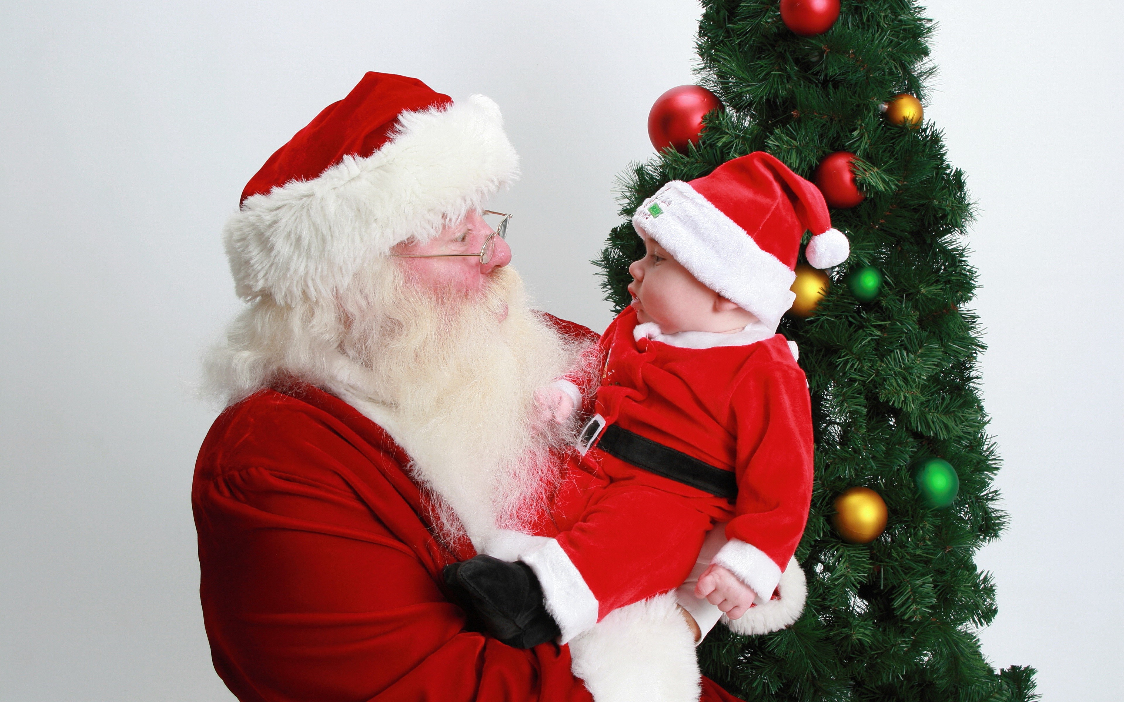 Santa Claus holding a baby in a Santa outfit HD Wallpaper