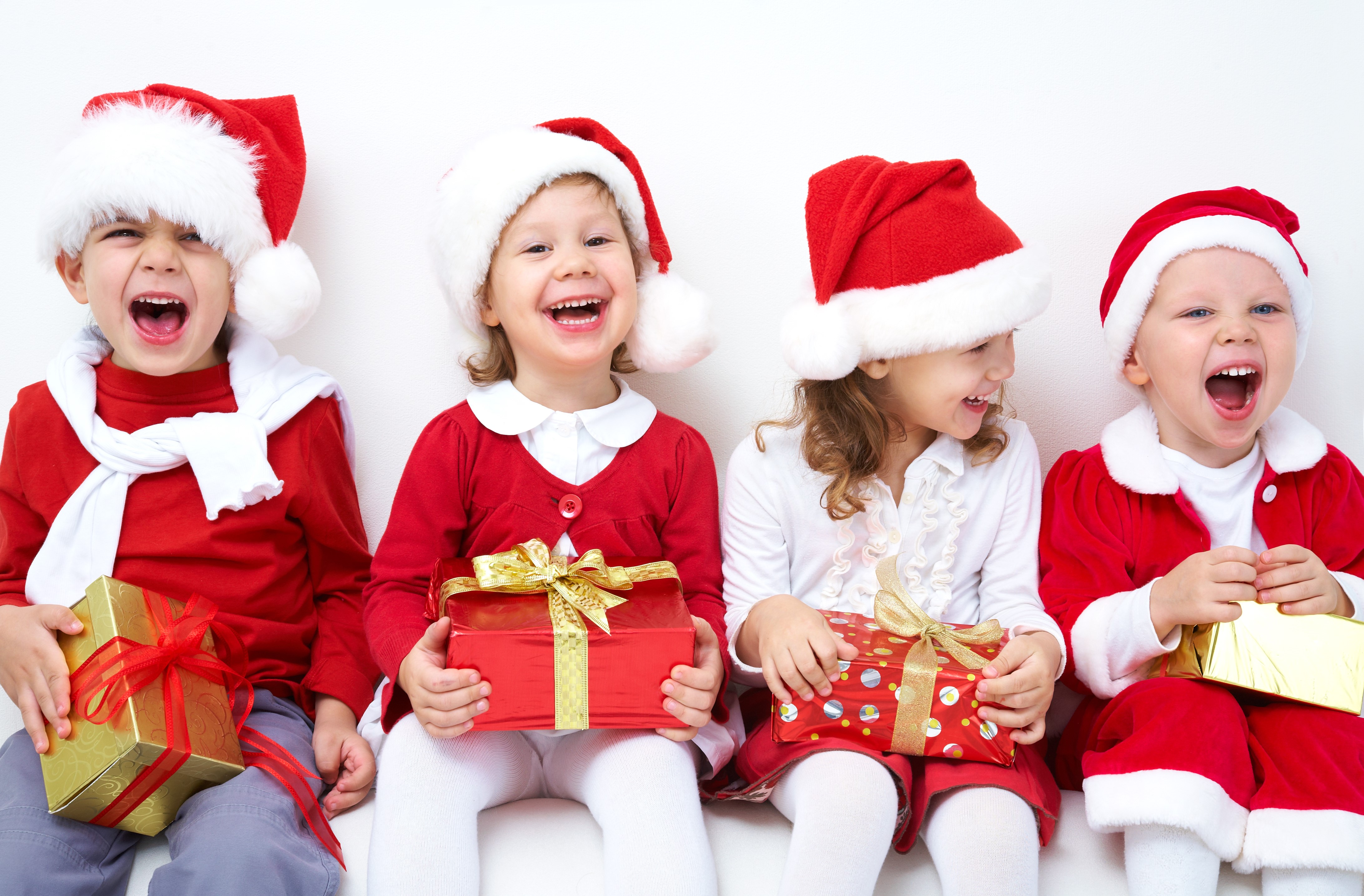 Four Children in Santa Hats with Christmas Gifts HD Wallpaper