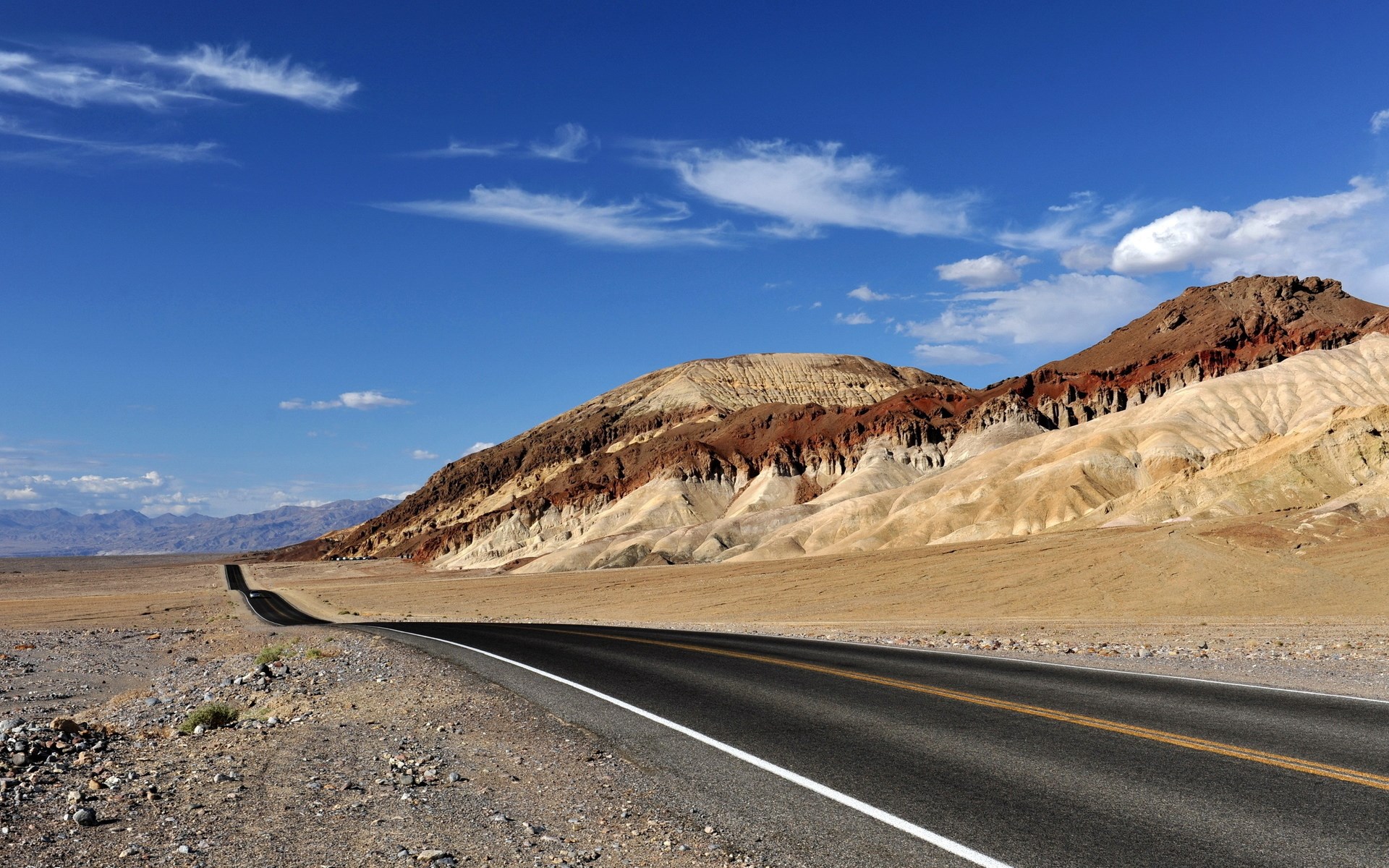 Desert road leading to colorful mountains under blue sky HD Wallpaper