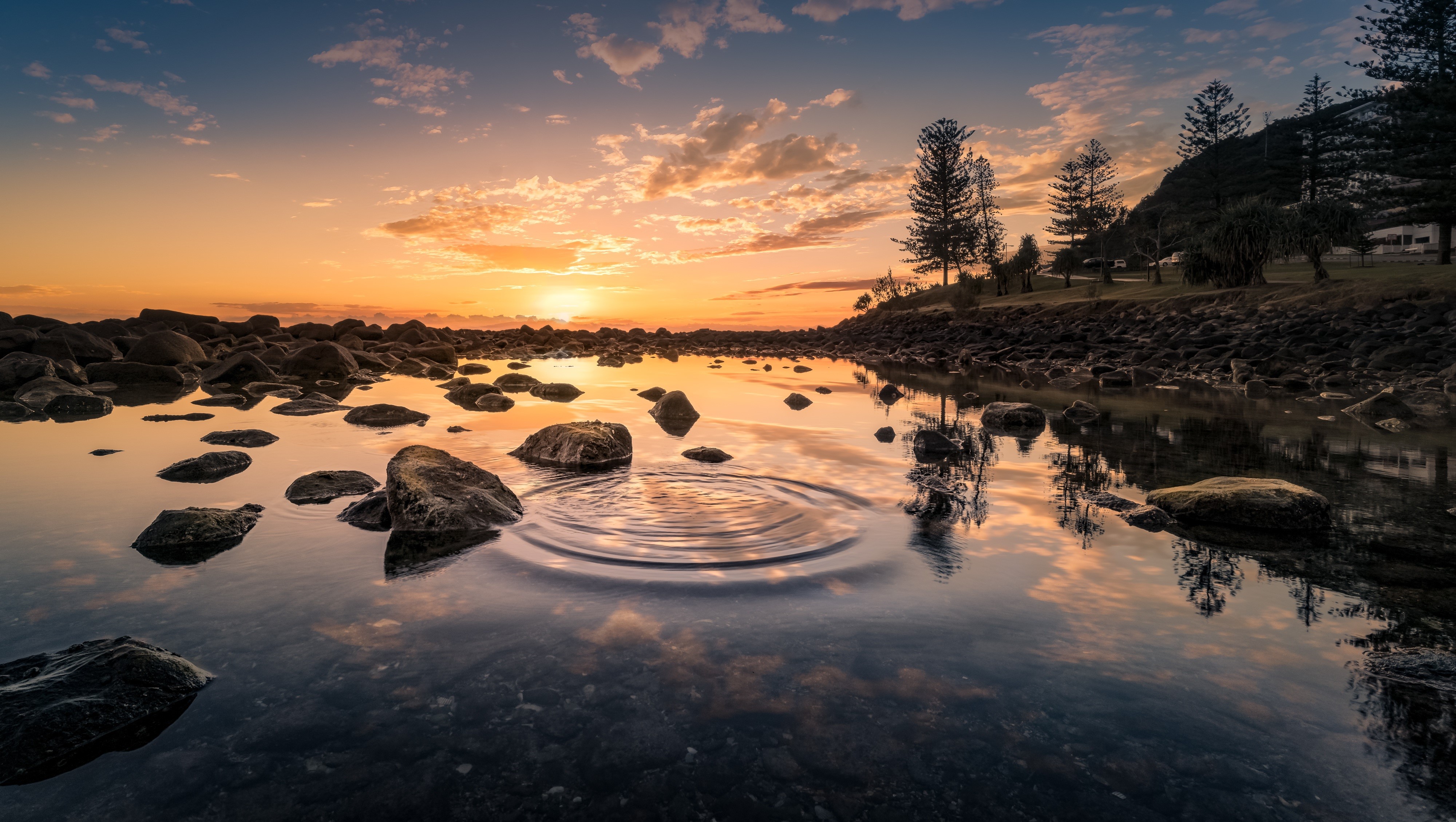Sunset over rocky shore with water reflections HD Wallpaper