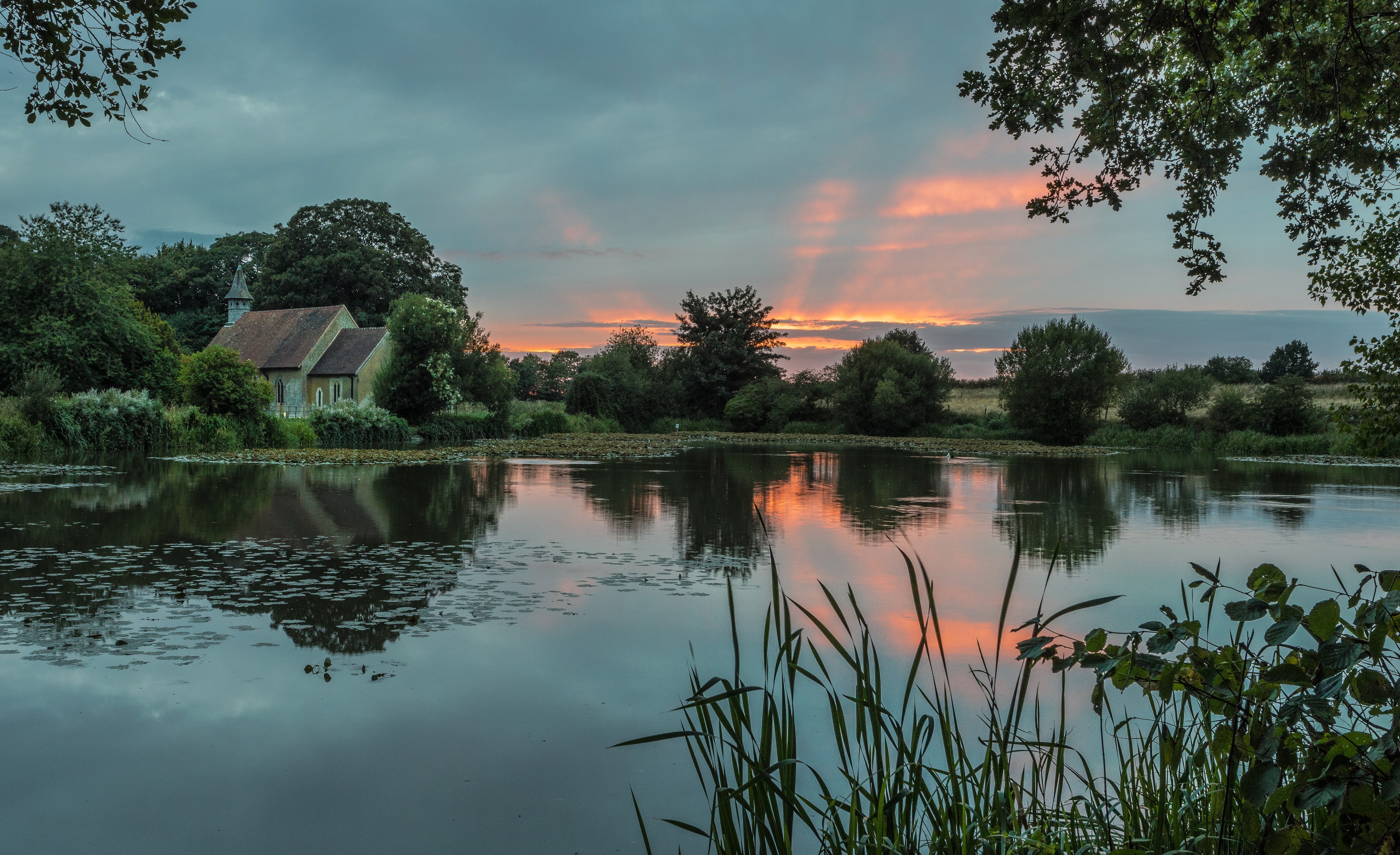 Church by a lake at sunset in Hartley Mauditt, England HD Wallpaper