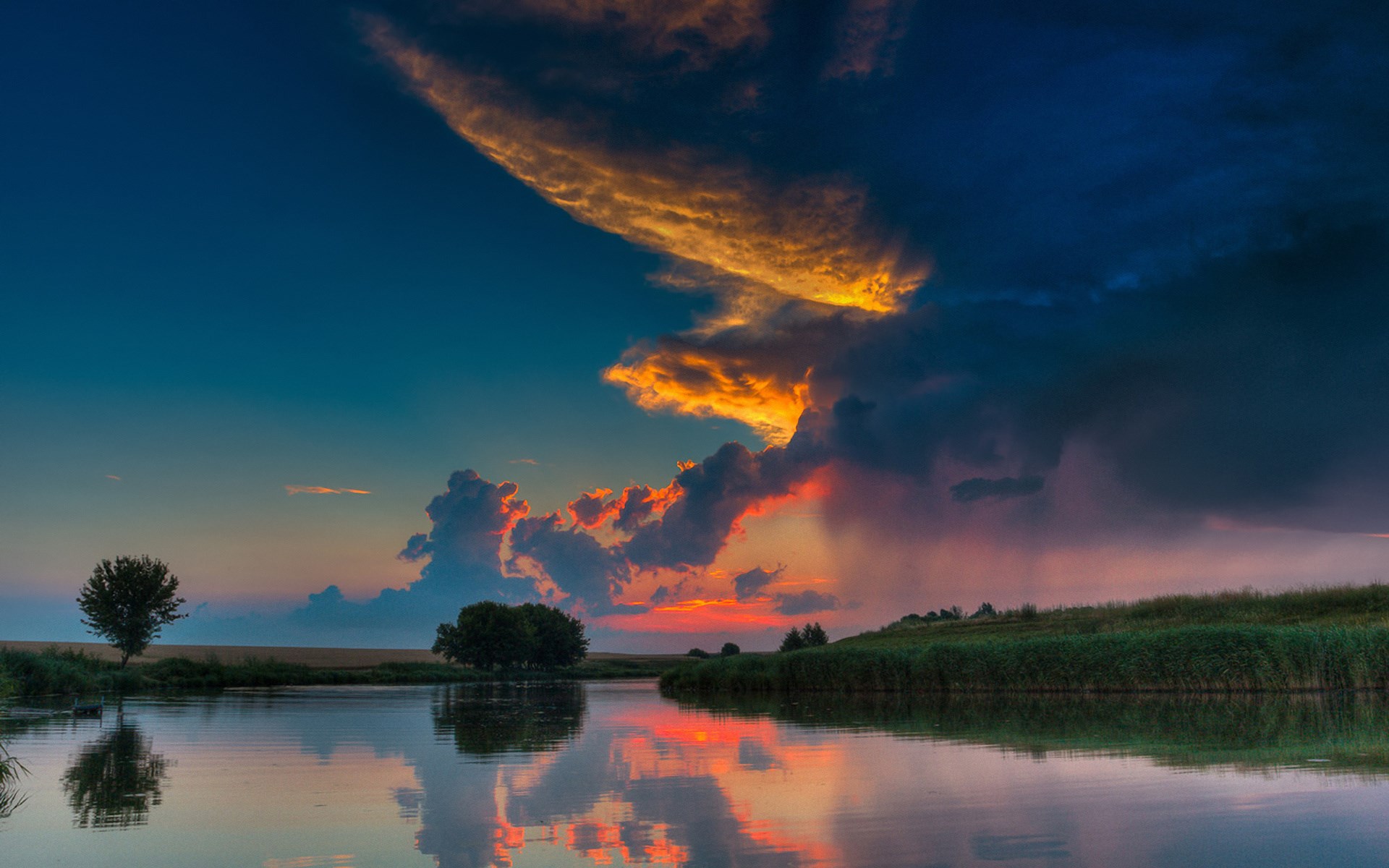 Sunset over a calm lake with dramatic clouds HD Wallpaper