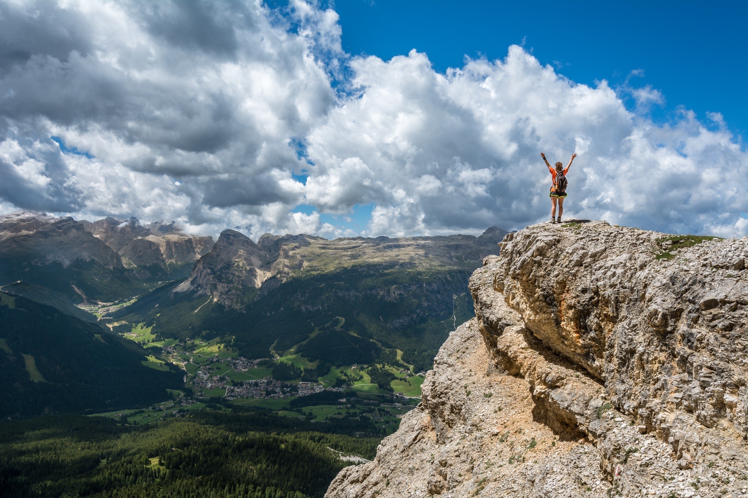 Woman on a mountain peak overlooking a valley HD Wallpaper