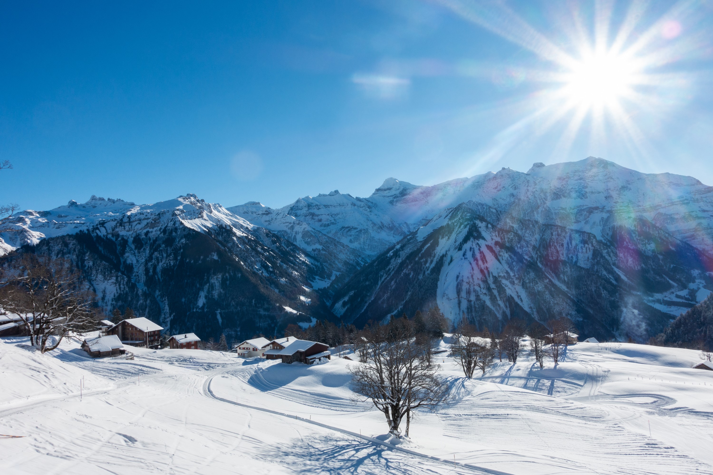 Braunwald, Switzerland: Snowy Mountains with Houses and Sun Rays HD Wallpaper