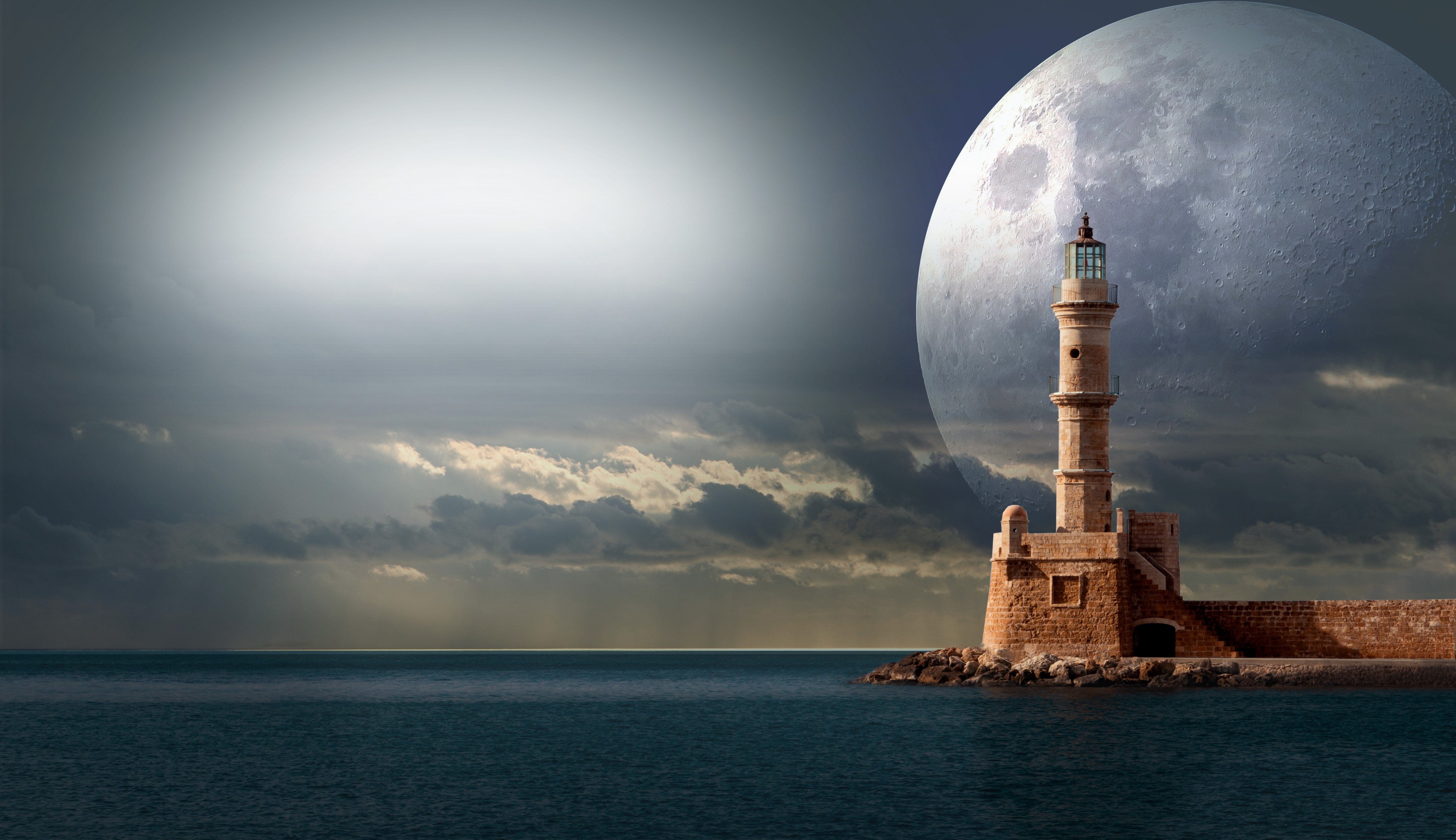 Lighthouse on a rocky shore with a large moon HD Wallpaper