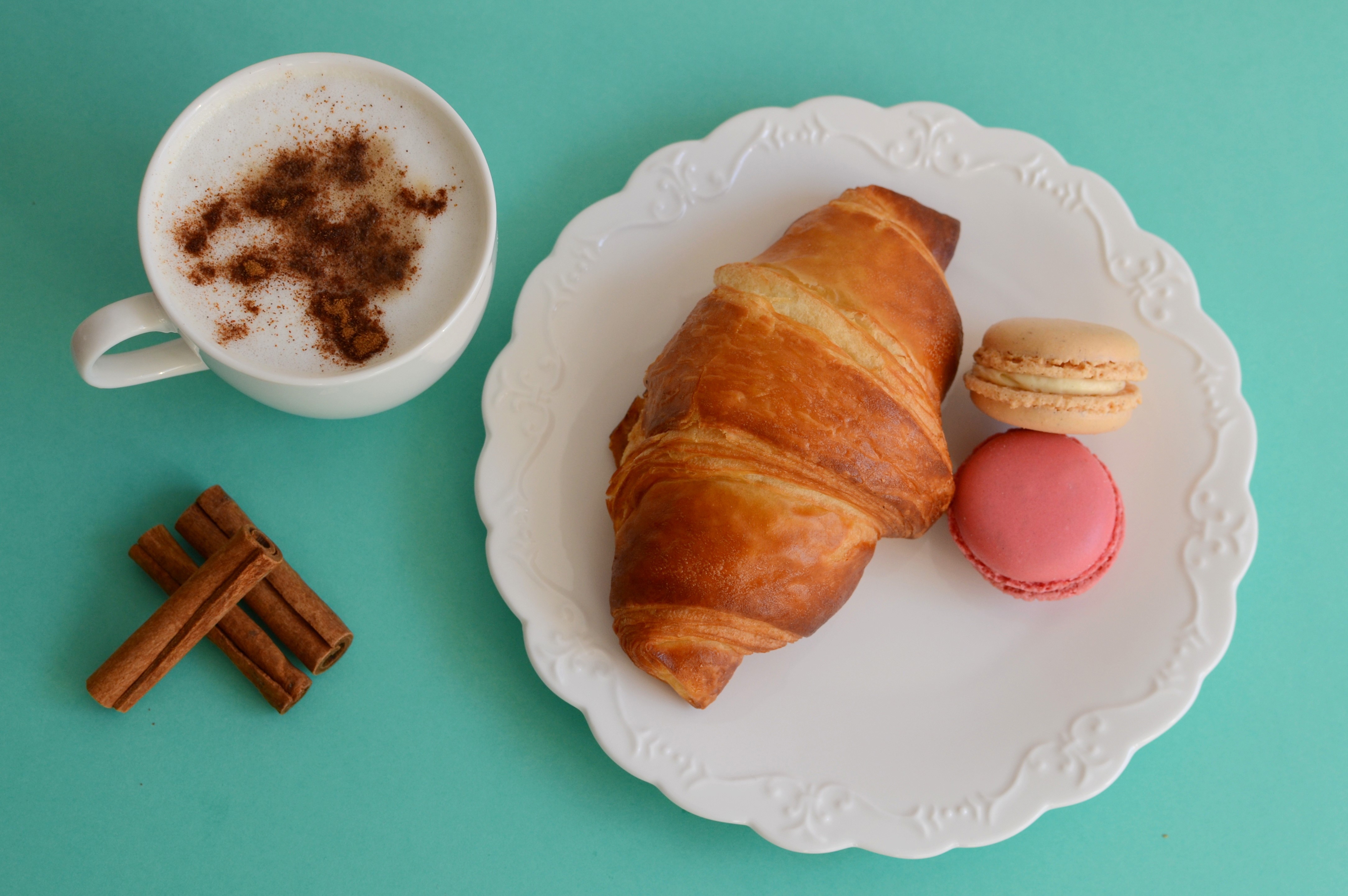 Cappuccino with cinnamon, croissant, and macarons on a plate HD Wallpaper