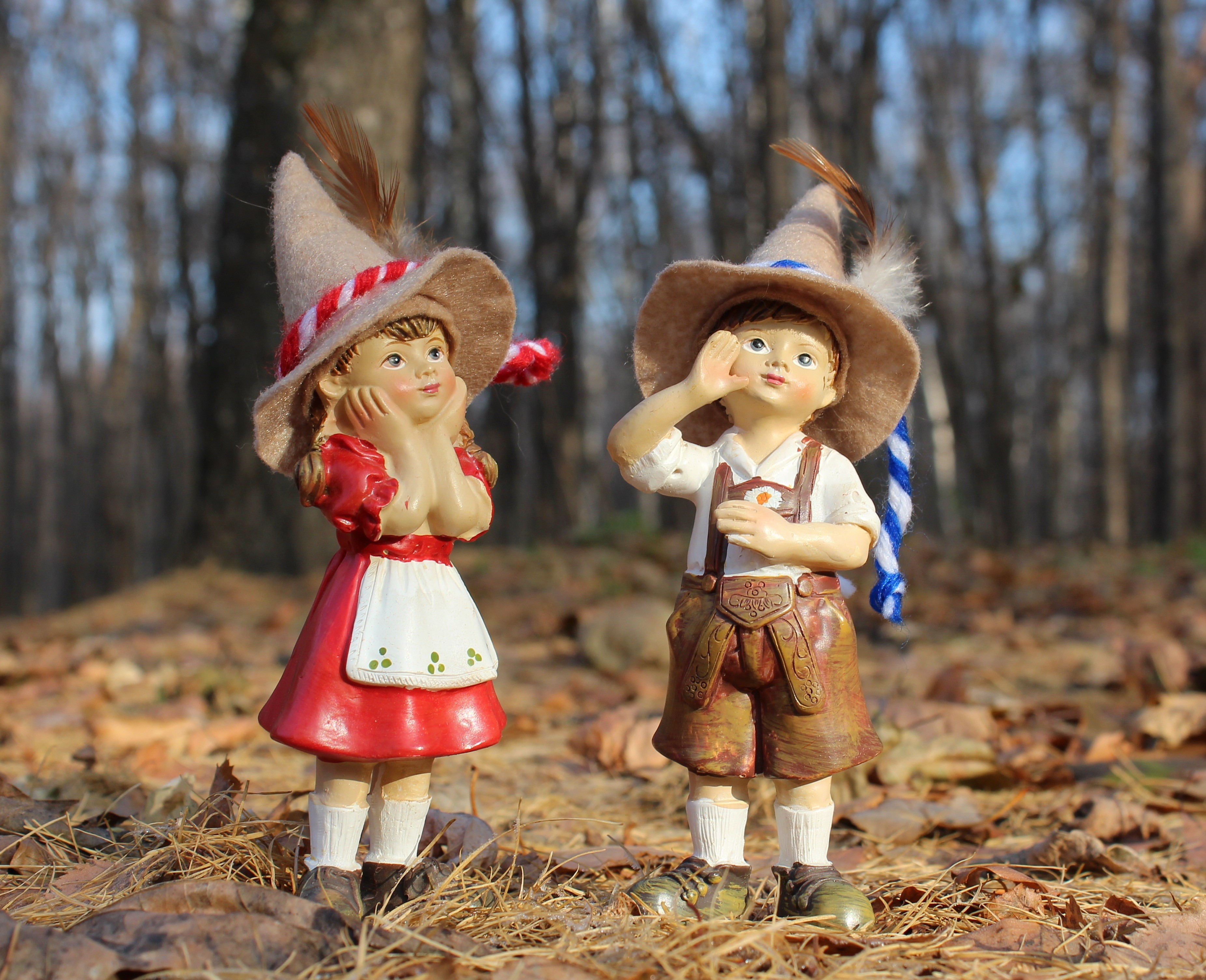 Two figurines of children in traditional German attire in autumn forest HD Wallpaper