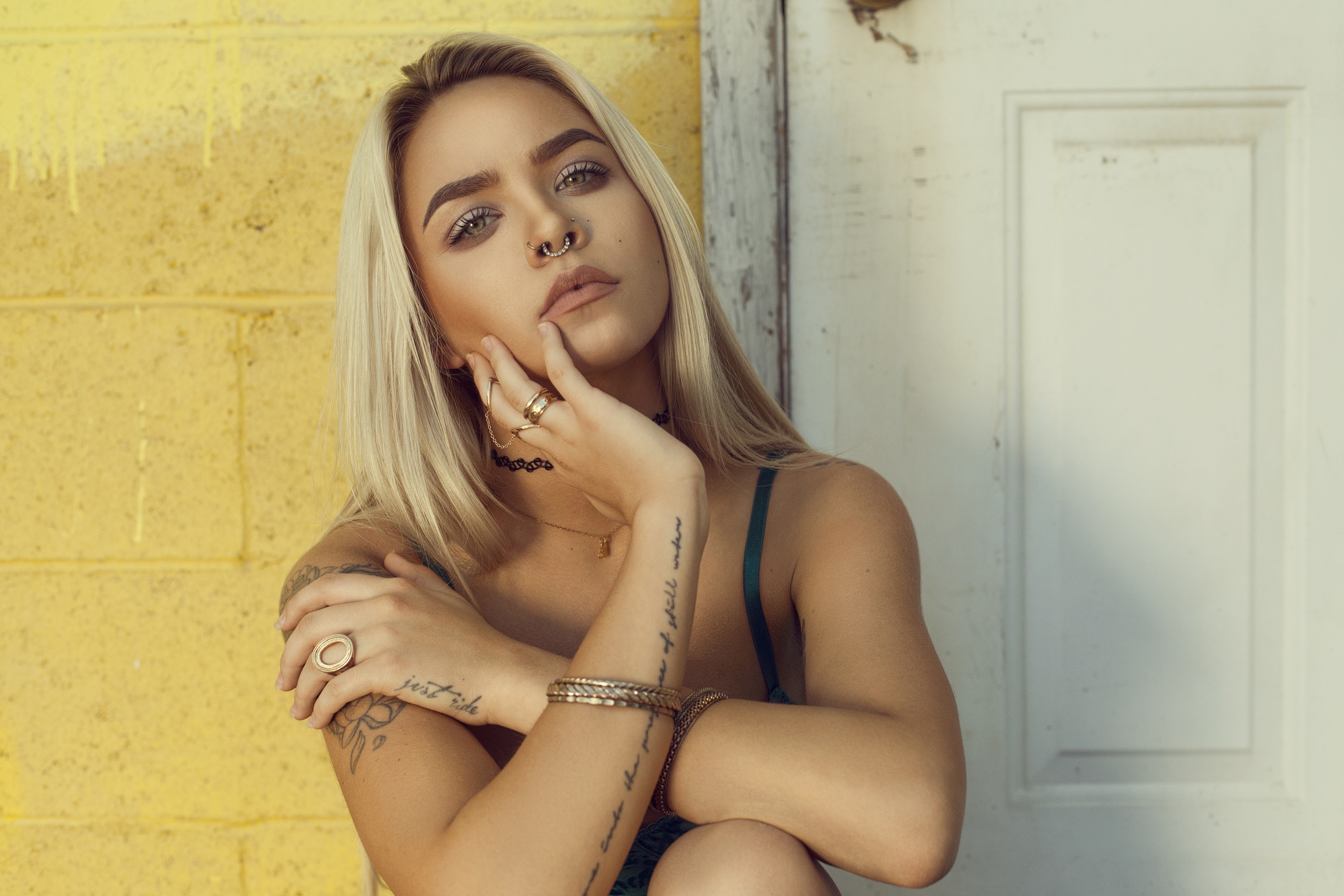 Blonde girl with tattoos and rings sitting HD Wallpaper