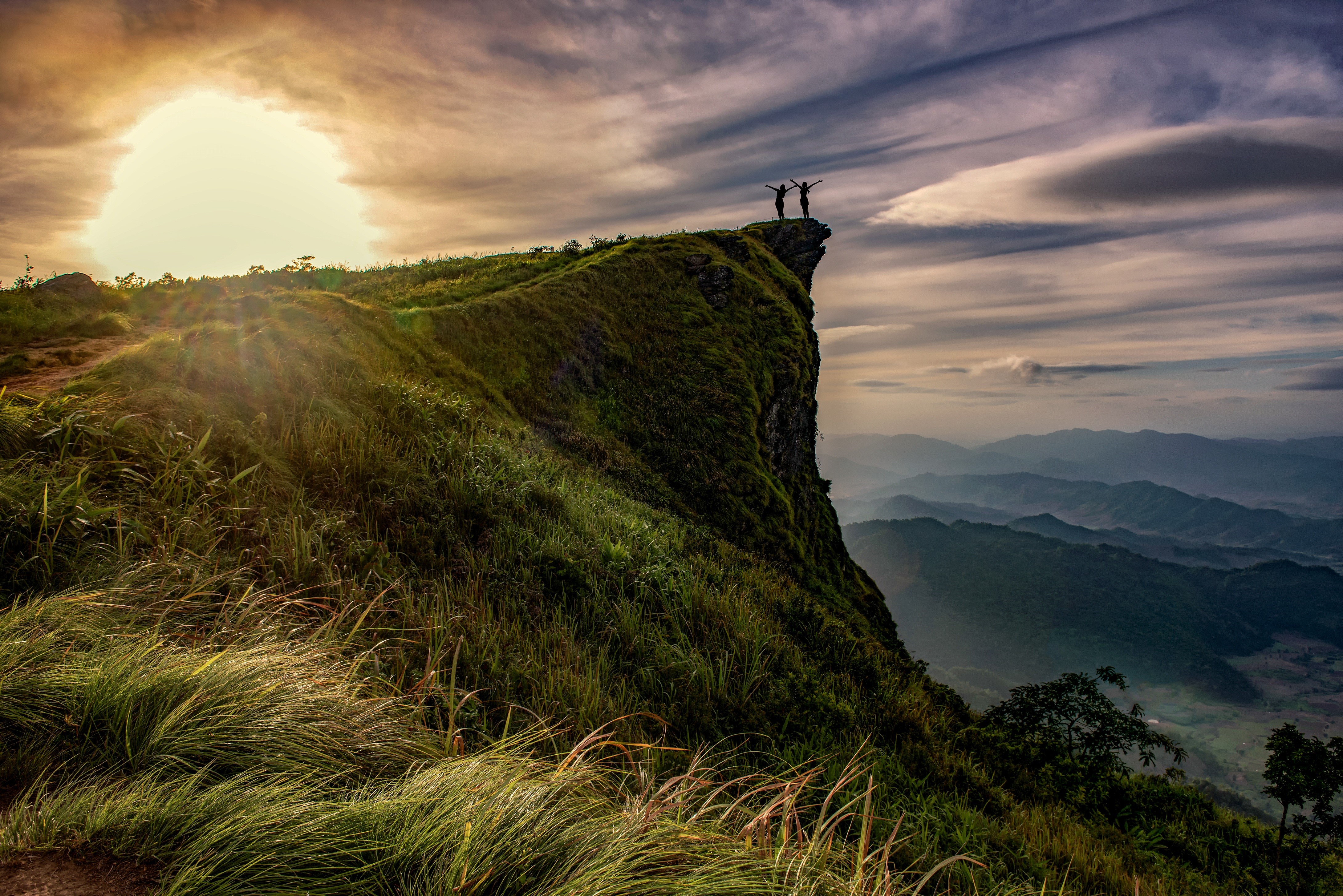 Two people on a cliff at sunset HD Wallpaper