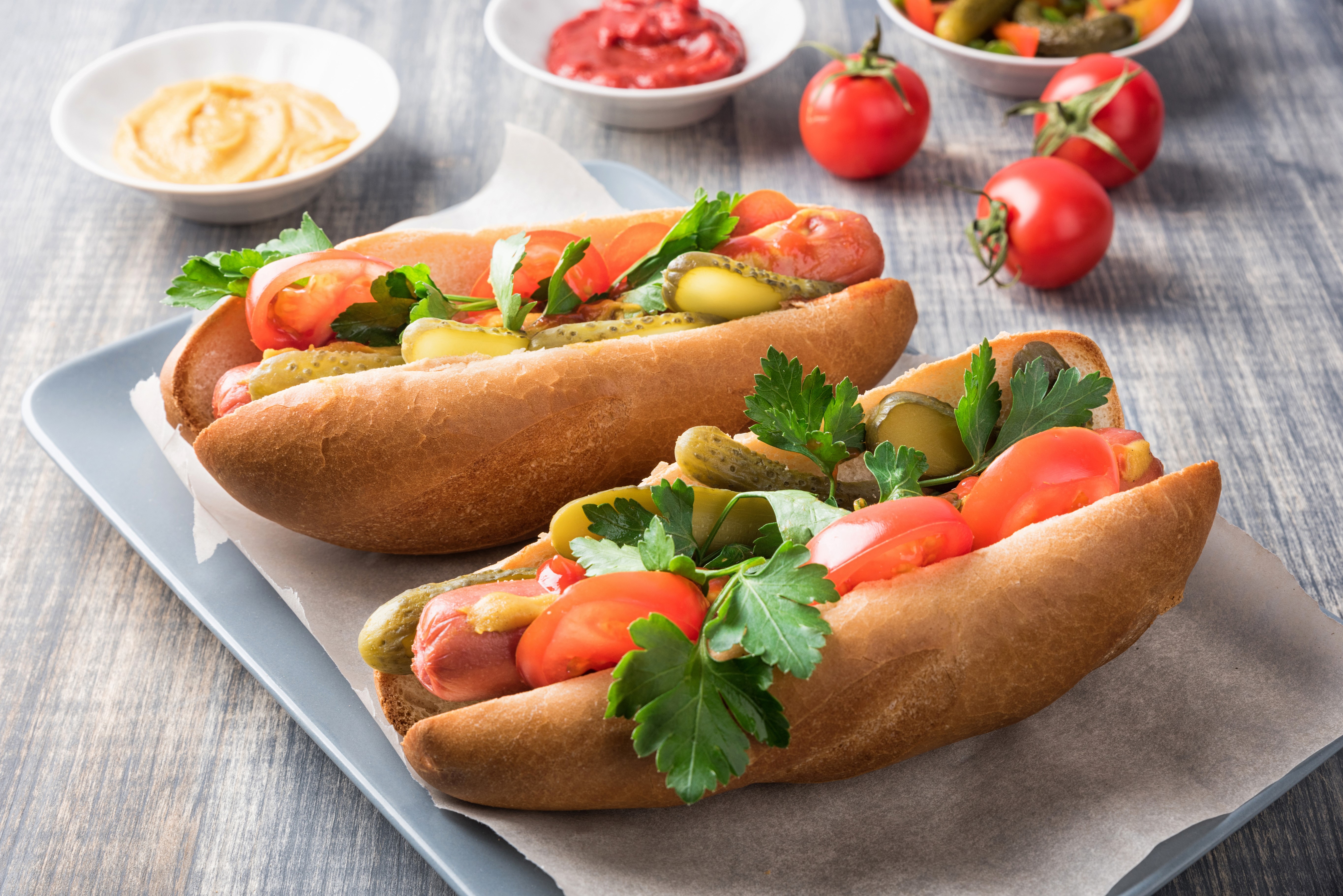 Two hot dogs with toppings on a plate HD Wallpaper