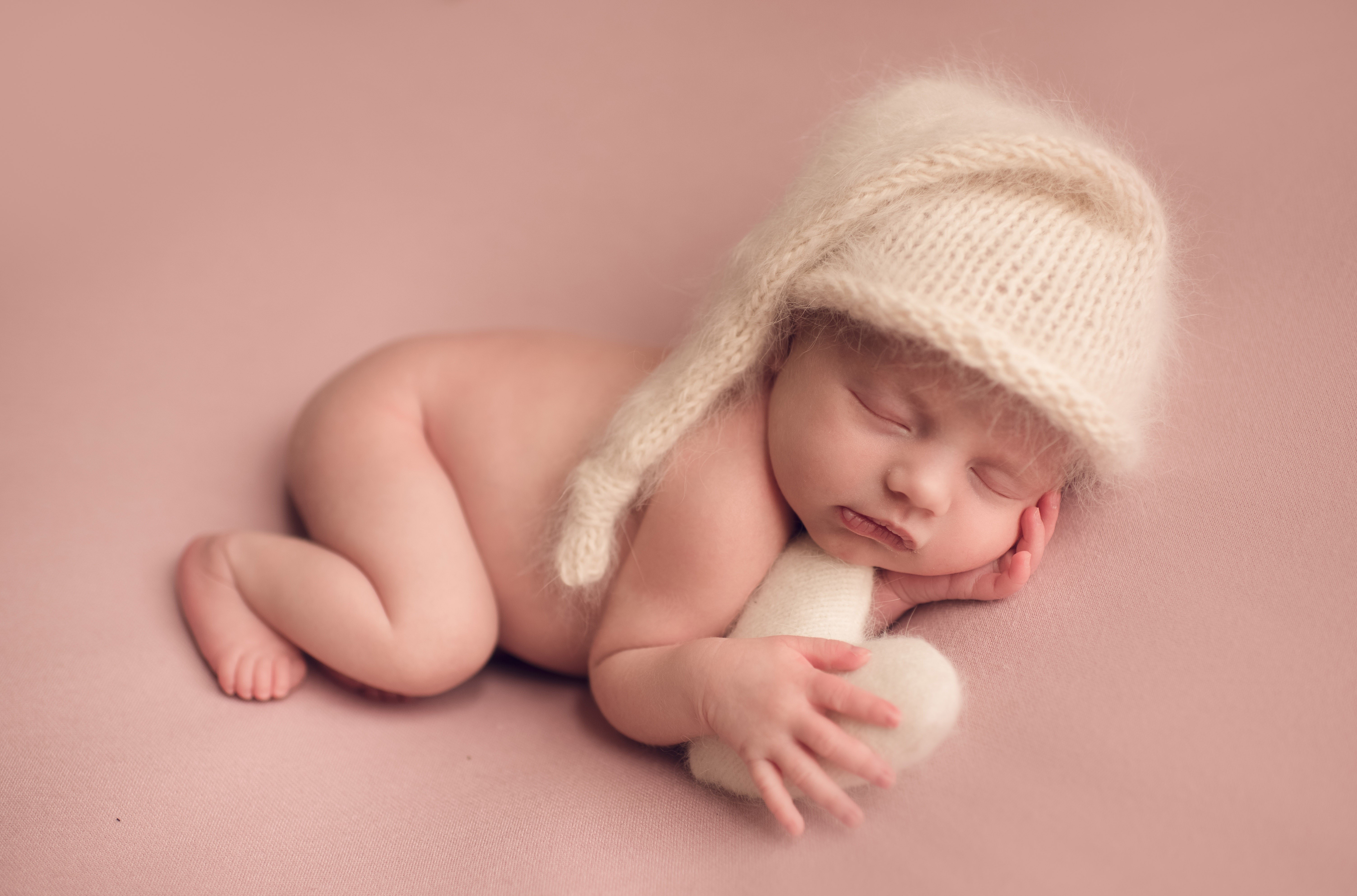 Infant sleeping in a knitted winter hat HD Wallpaper