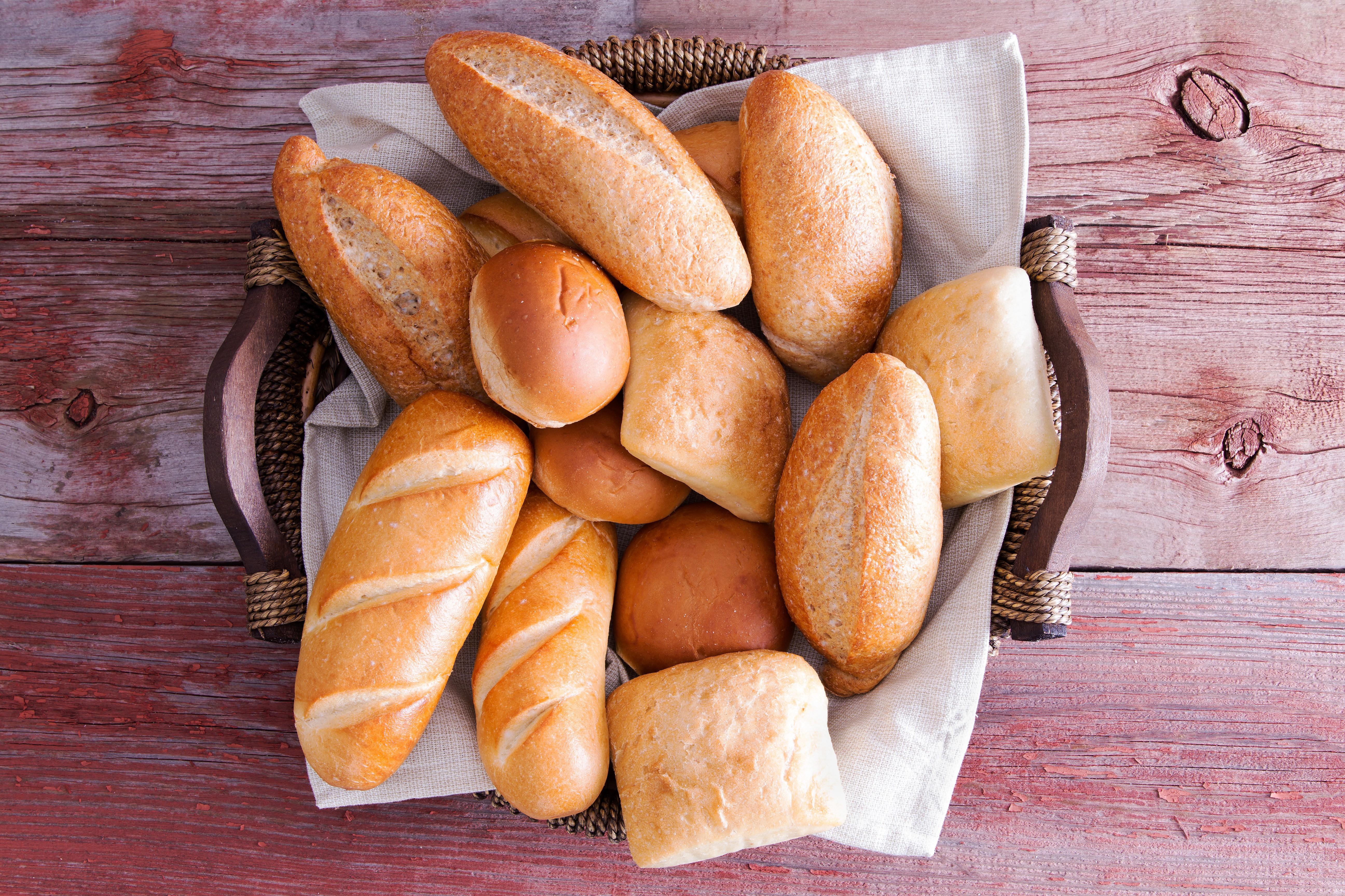 Basket of assorted bread rolls and loaves on wooden planks HD Wallpaper