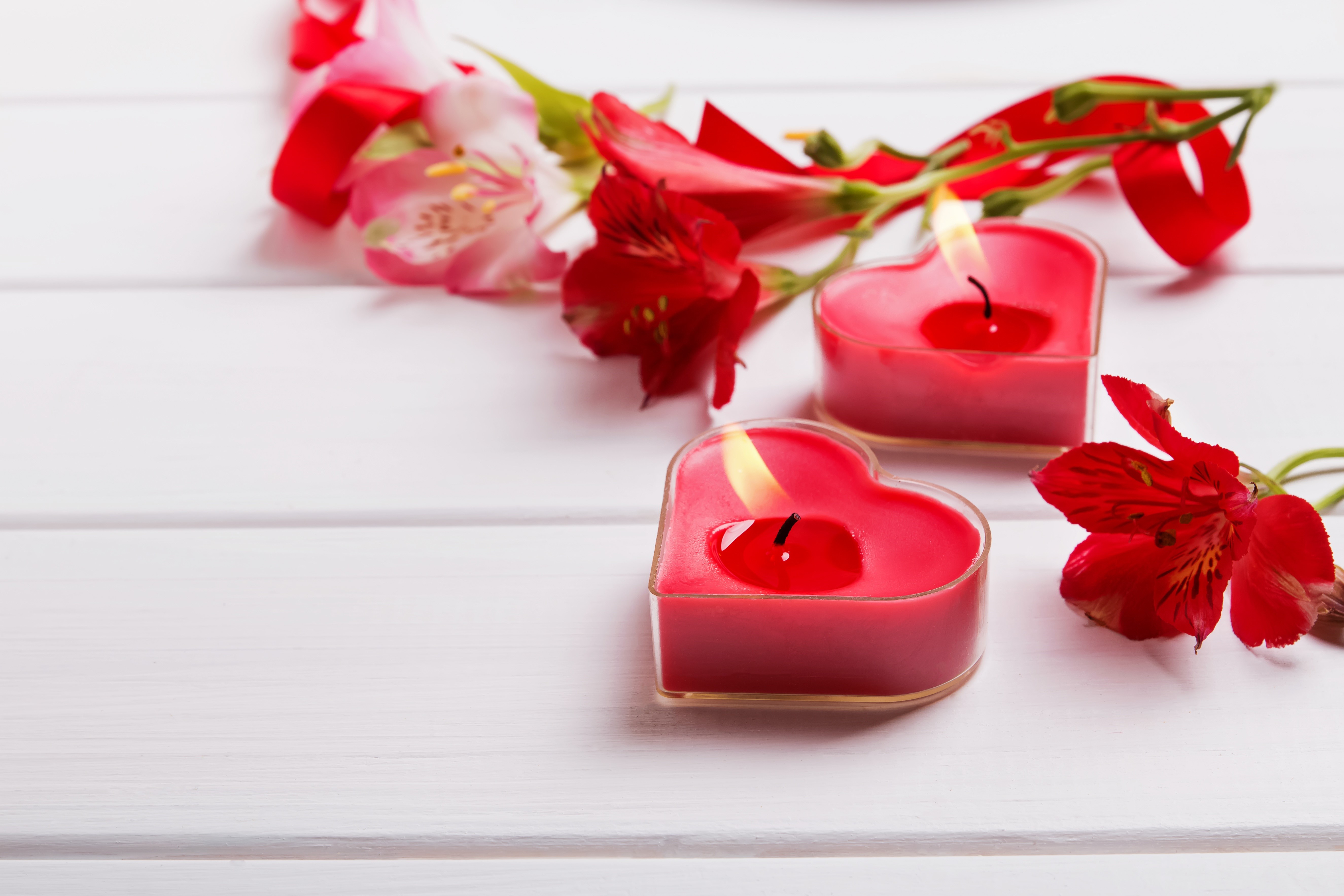 Heart-shaped candles and flowers on white wooden table HD Wallpaper