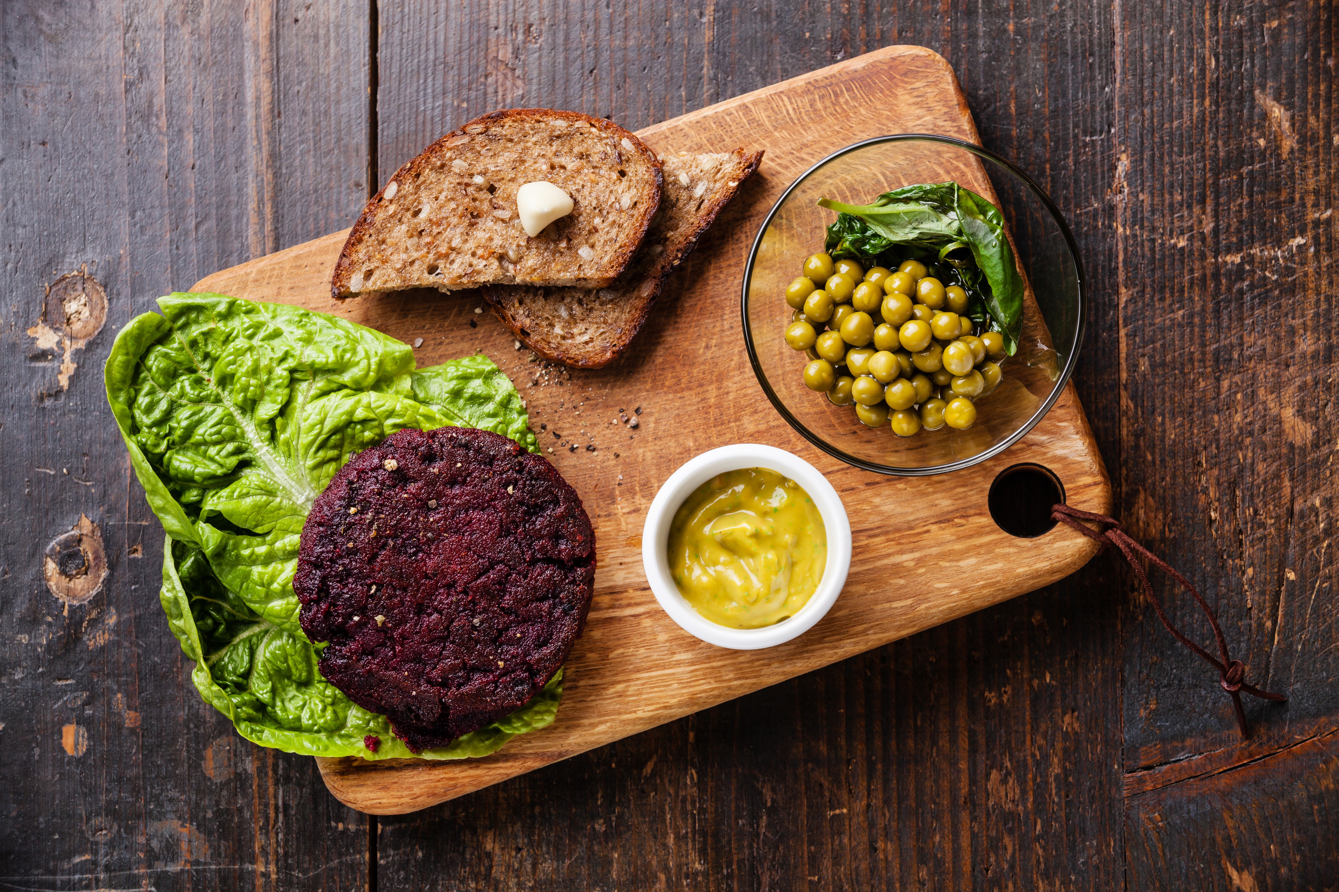 Beetroot burger with peas and bread on a cutting board HD Wallpaper
