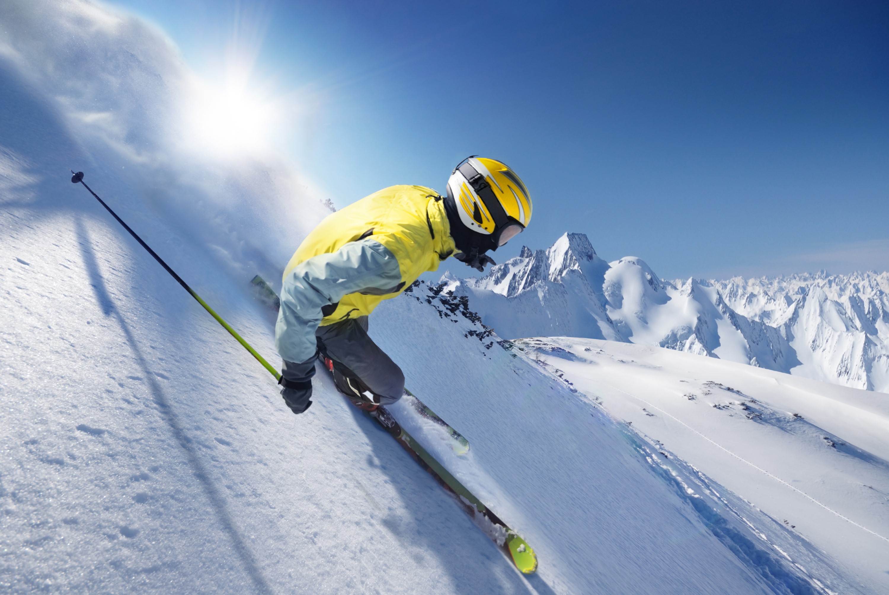 Skier in yellow jacket skiing down a snowy mountain HD Wallpaper