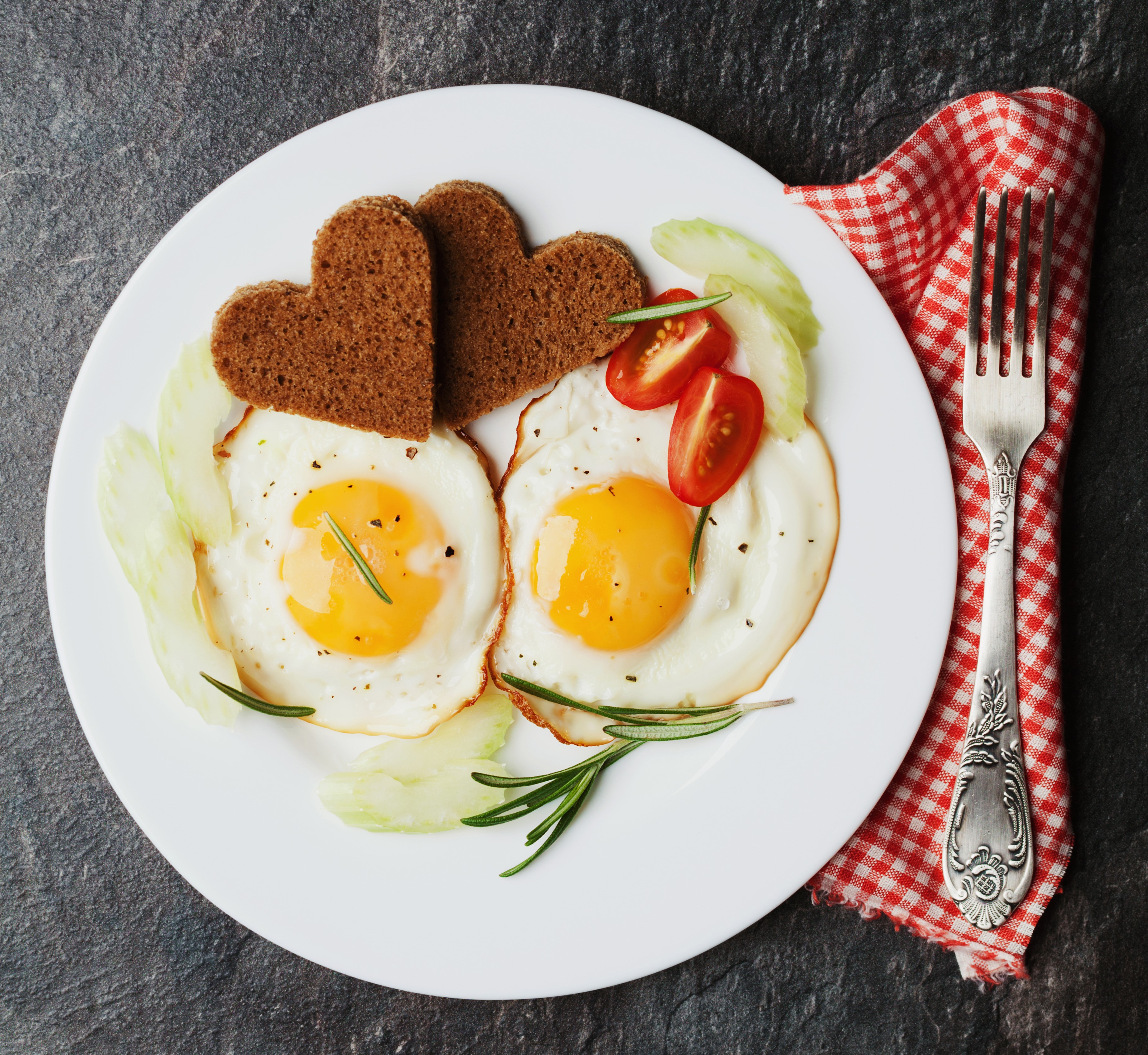 Two heart-shaped toasts with fried eggs and cherry tomatoes on a plate HD Wallpaper