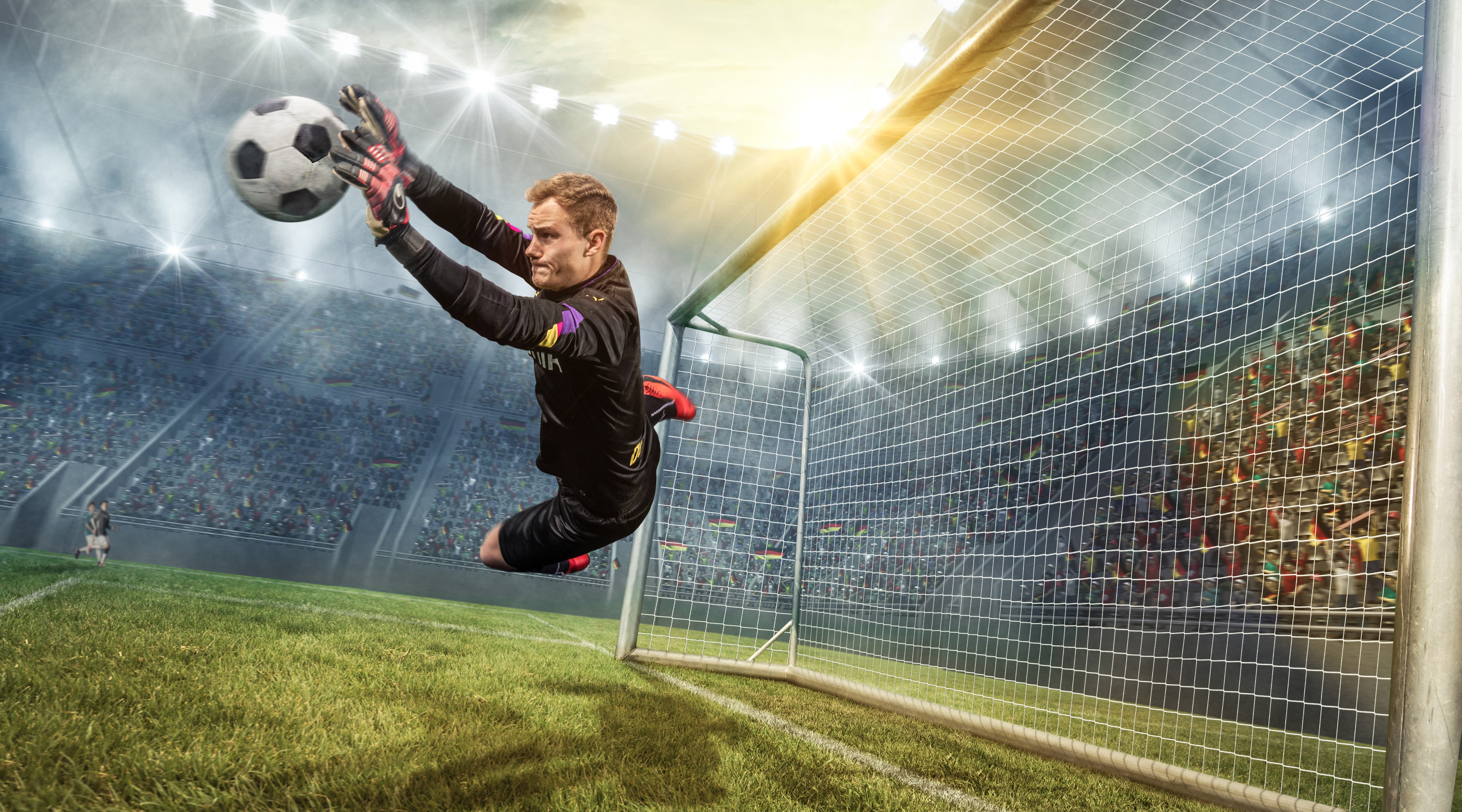 Goalkeeper jumping to catch a soccer ball in a stadium HD Wallpaper