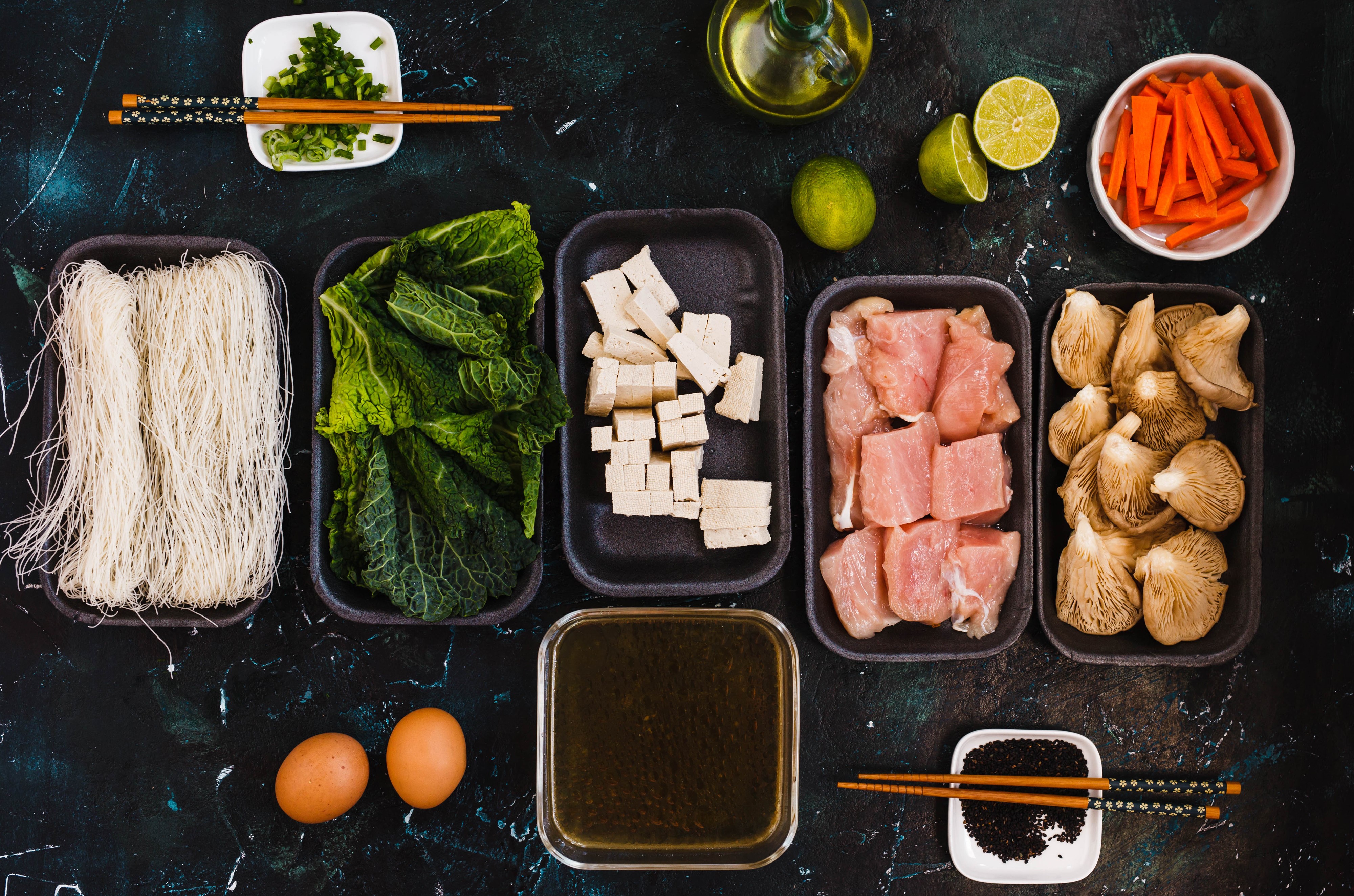Ingredients for Asian Soup: Noodles, Tofu, Meat, Mushrooms, Vegetables, Eggs, Lime, Carrots, Oil, Sesame Seeds HD Wallpaper