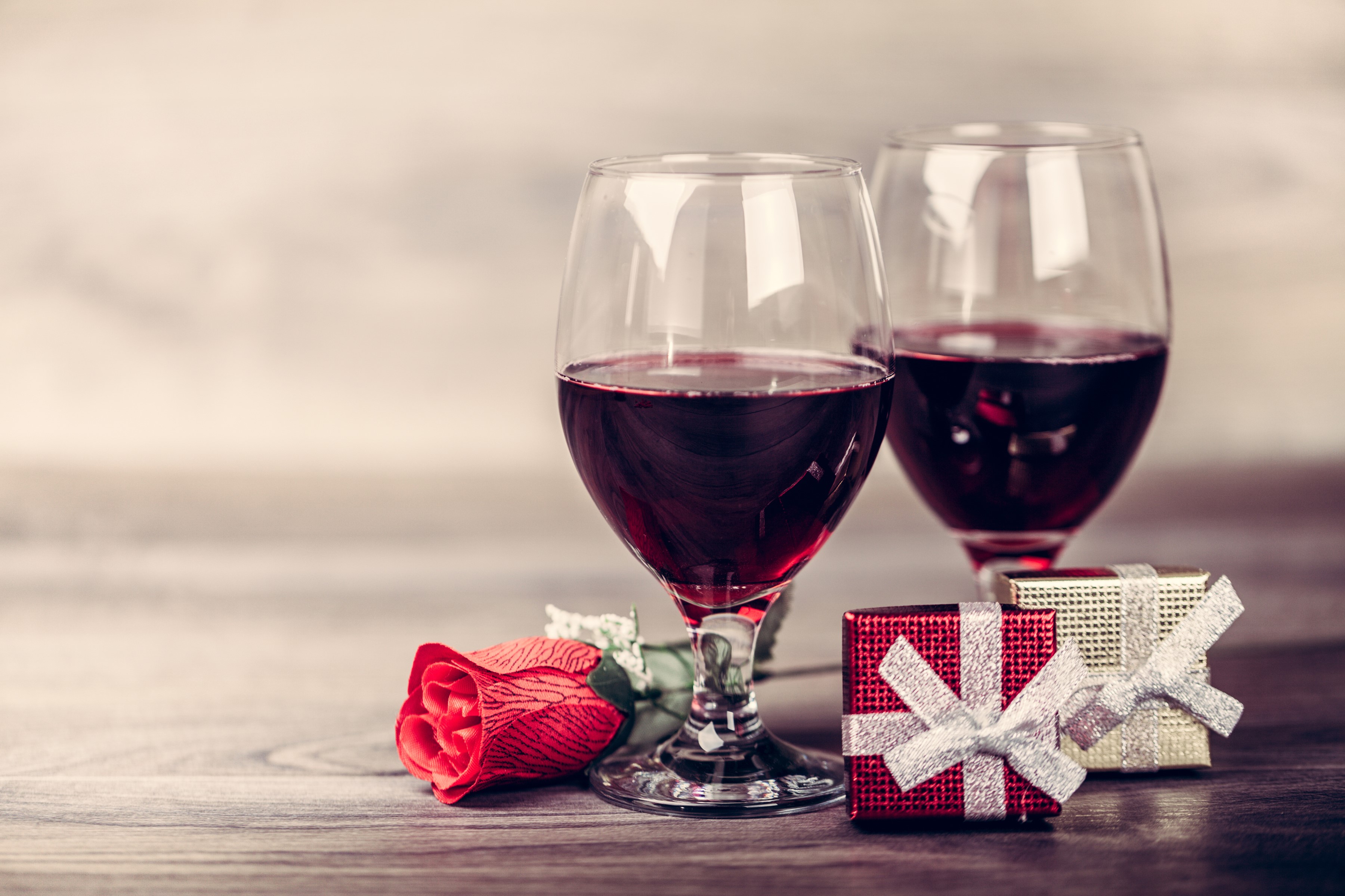 Two glasses of red wine with rose and gifts HD Wallpaper