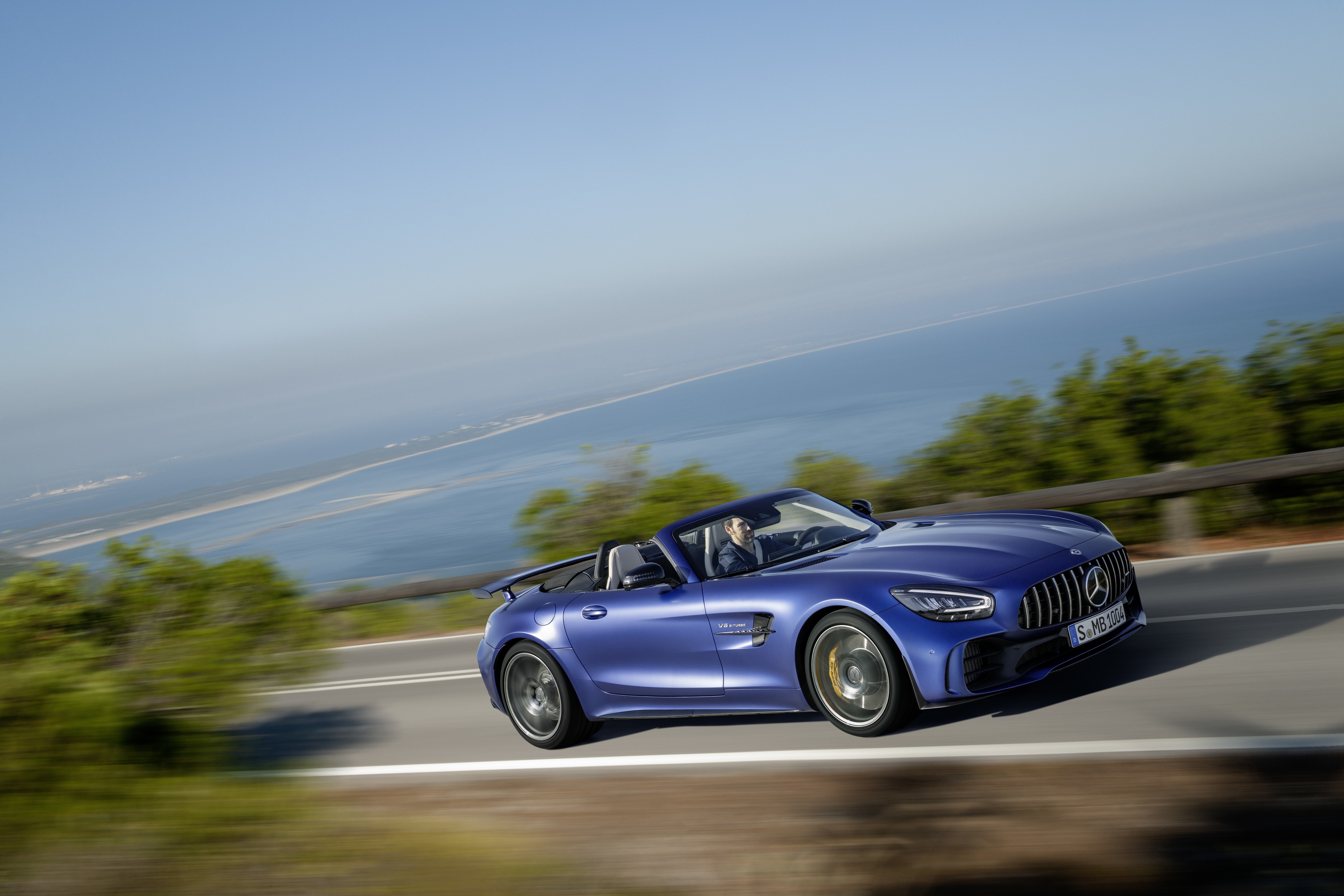 Blue Mercedes-Benz GT R AMG Cabriolet driving on a coastal road HD Wallpaper