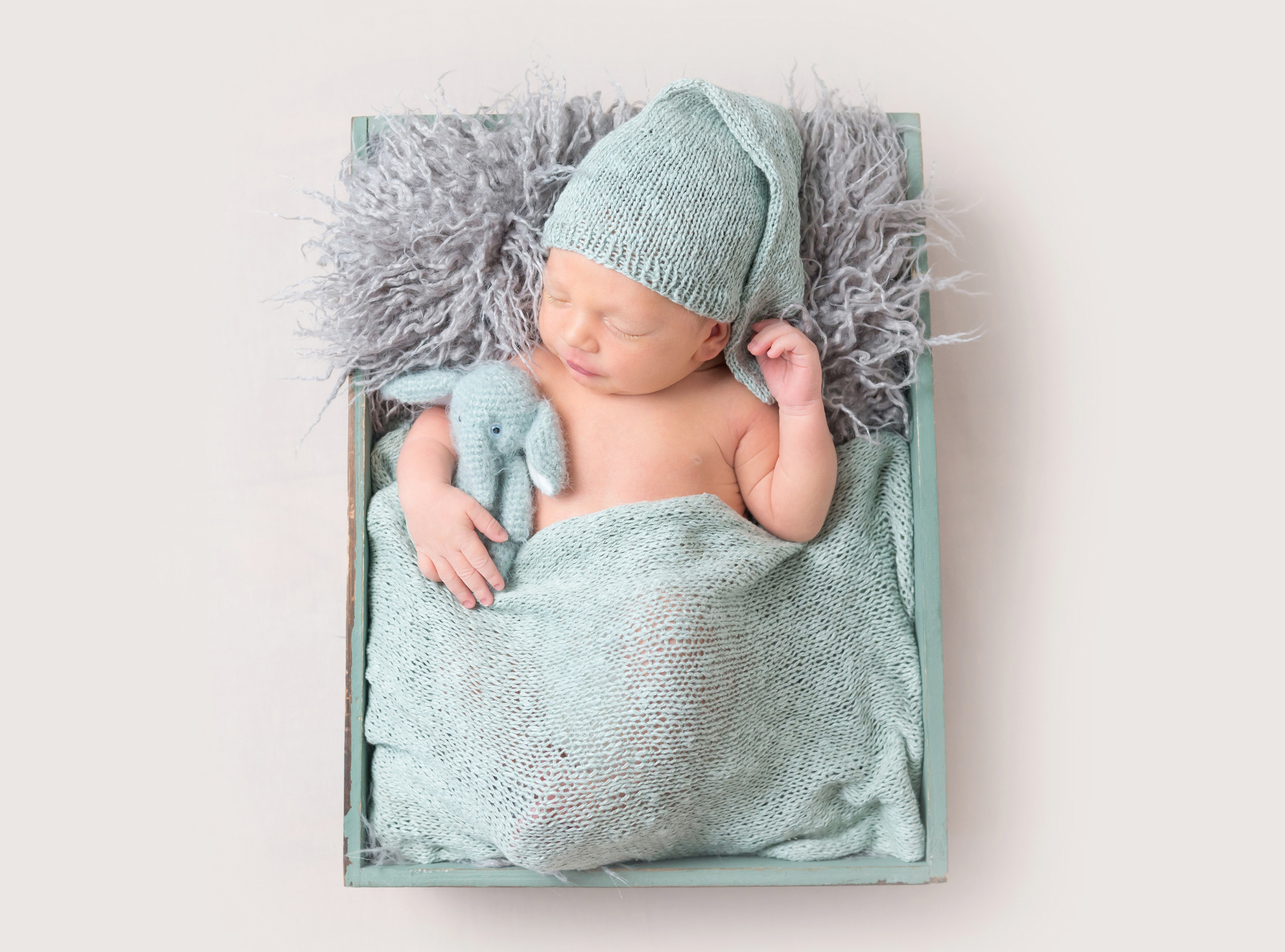 Newborn baby sleeping in a wooden box with a knitted hat HD Wallpaper