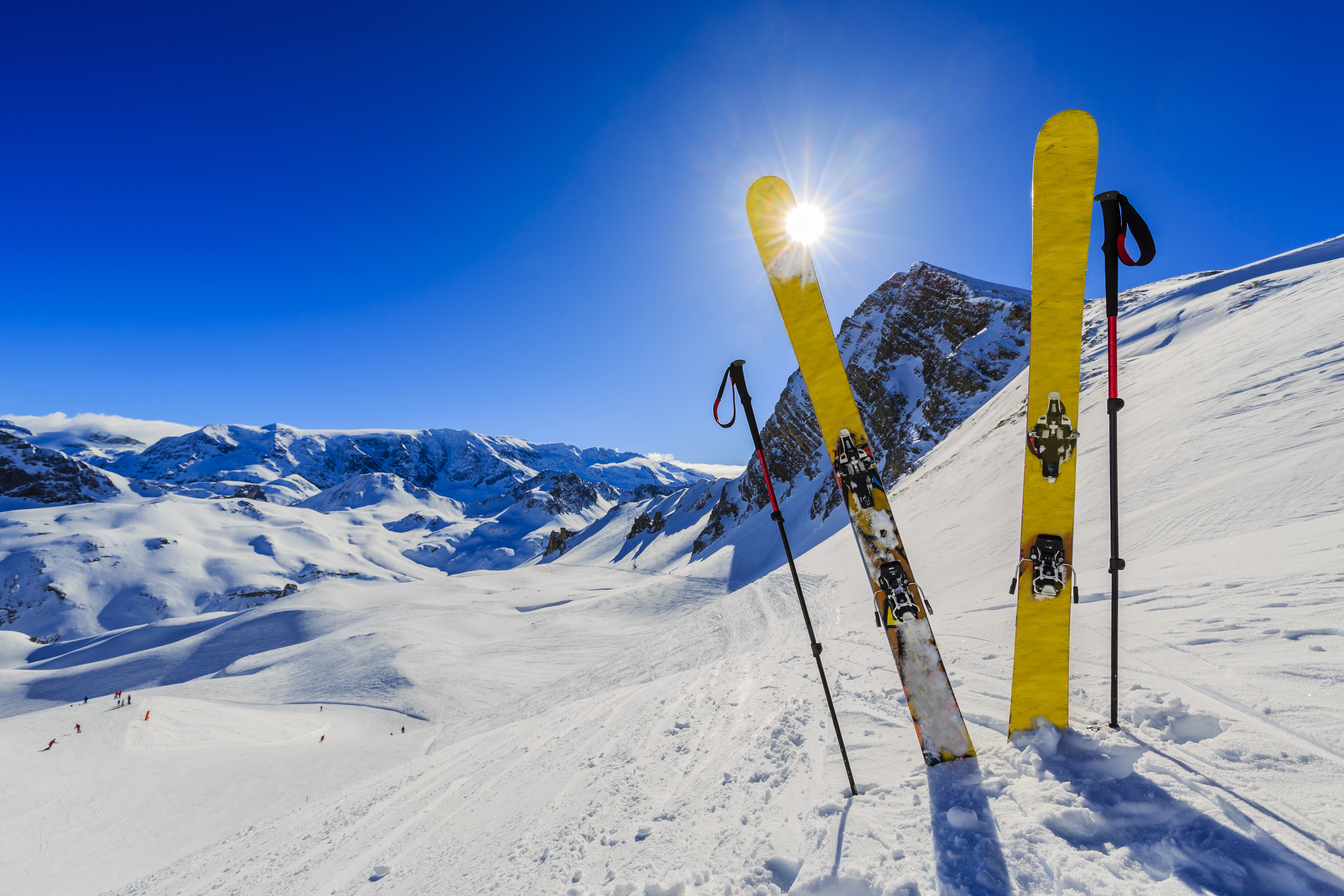 Yellow skis and poles in snowy mountains under sun HD Wallpaper
