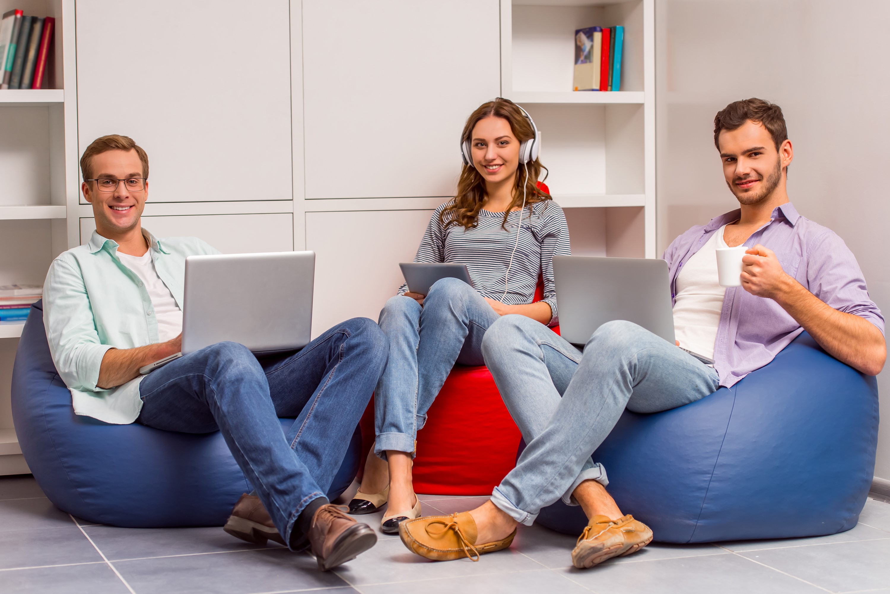 Three people with laptops and tablet in beanbag chairs HD Wallpaper