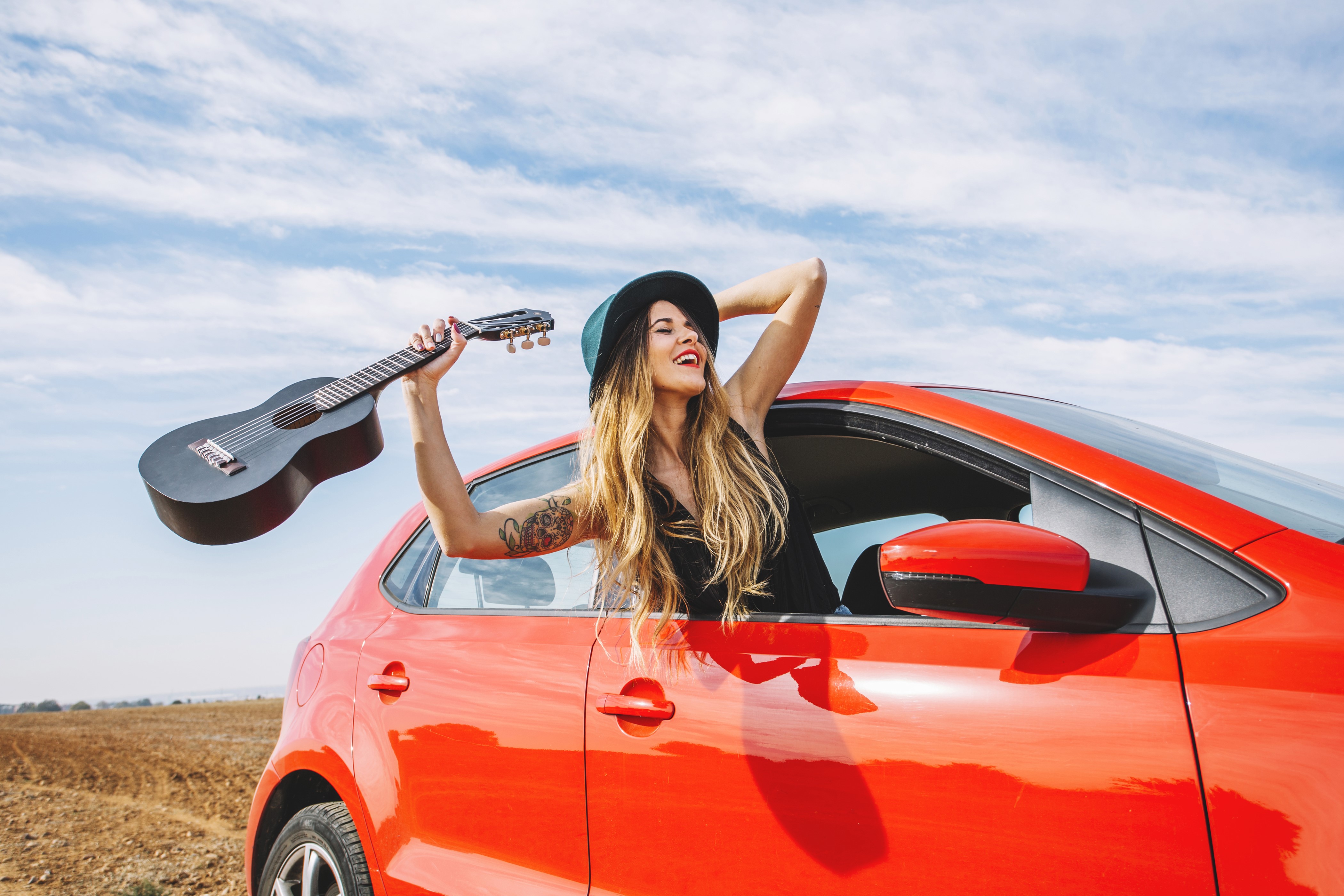 Woman with guitar in a red car HD Wallpaper