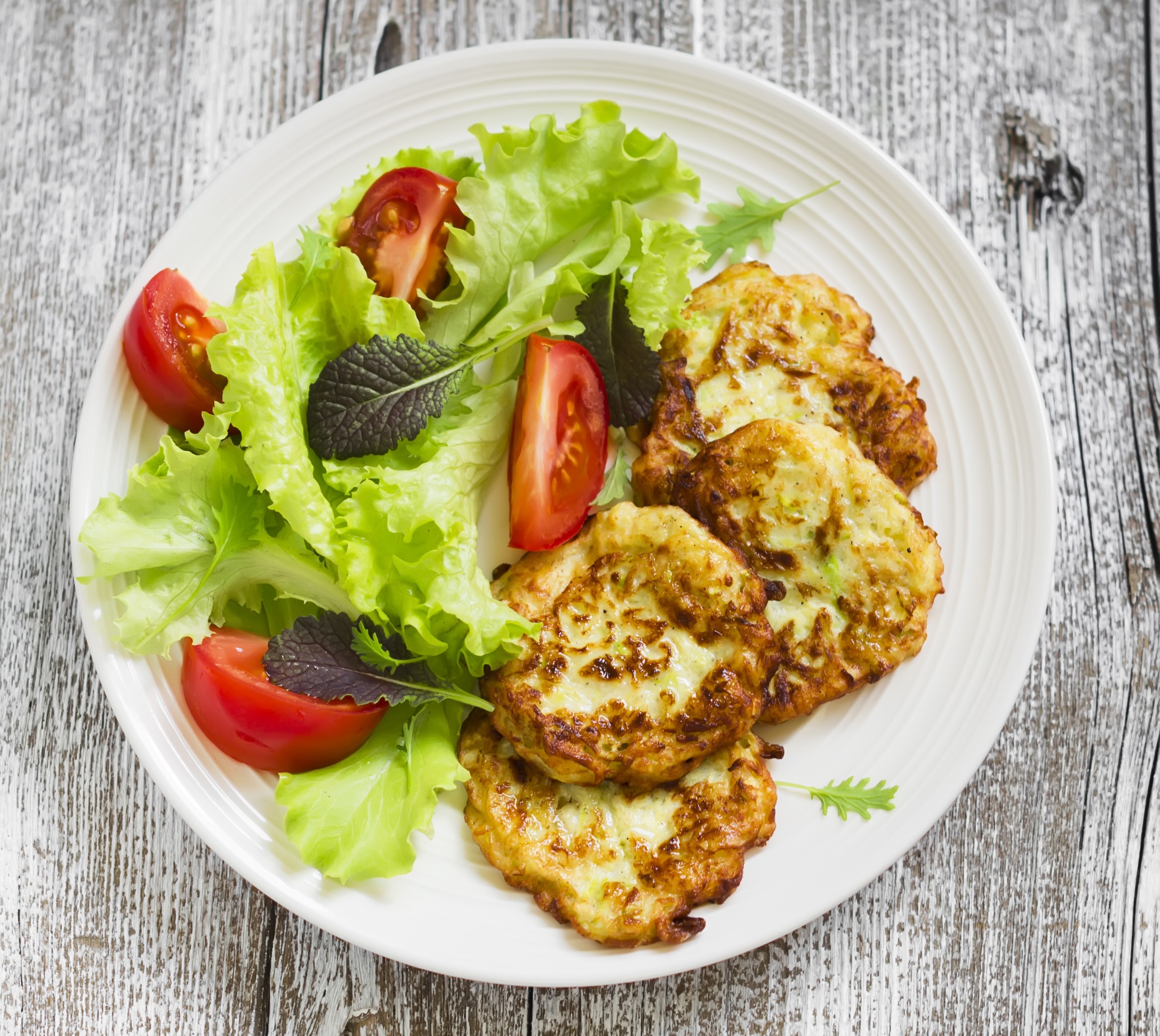 Zucchini fritters with salad and tomatoes on a plate HD Wallpaper