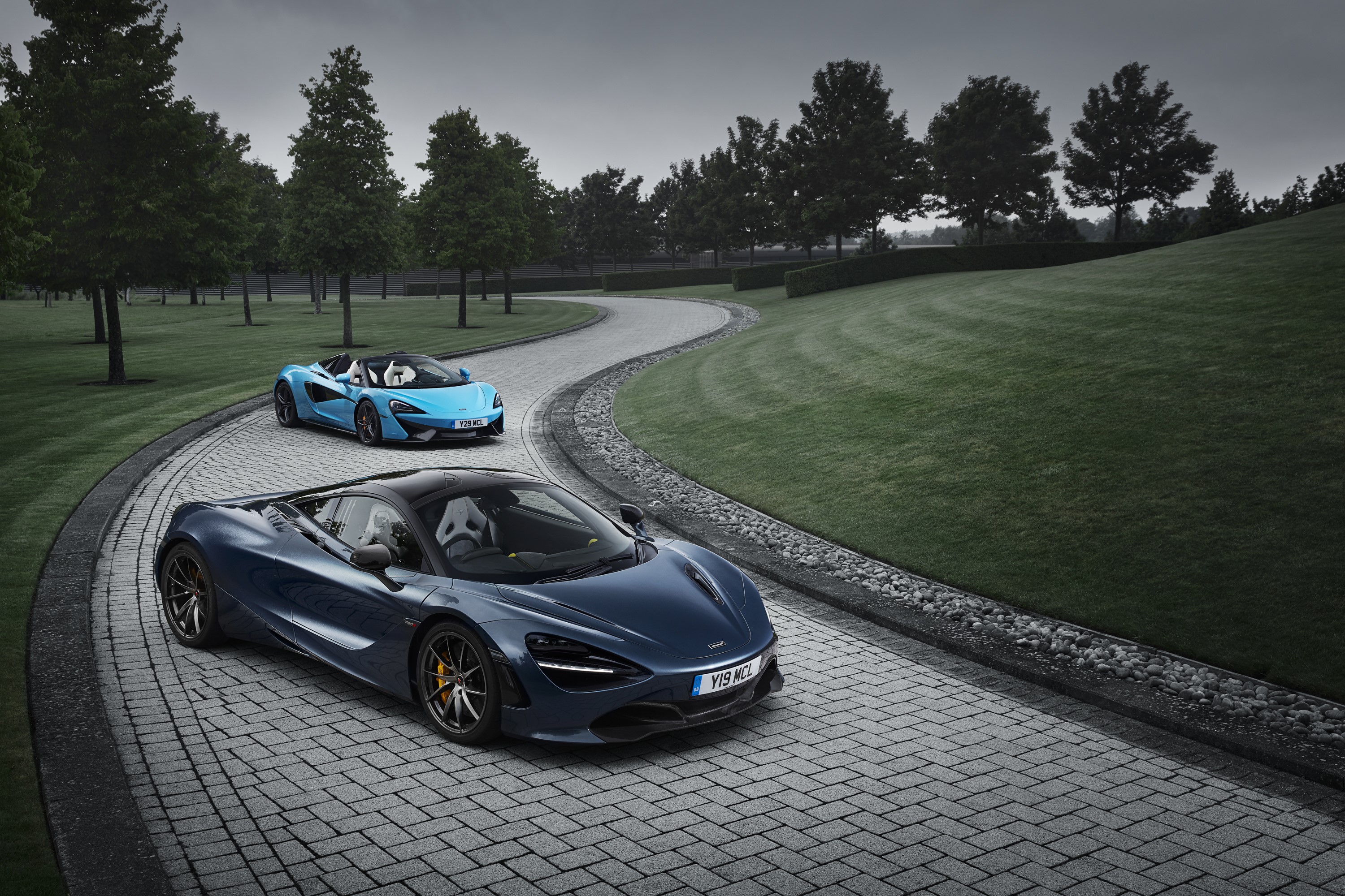 Two McLaren sports cars on a paved driveway HD Wallpaper