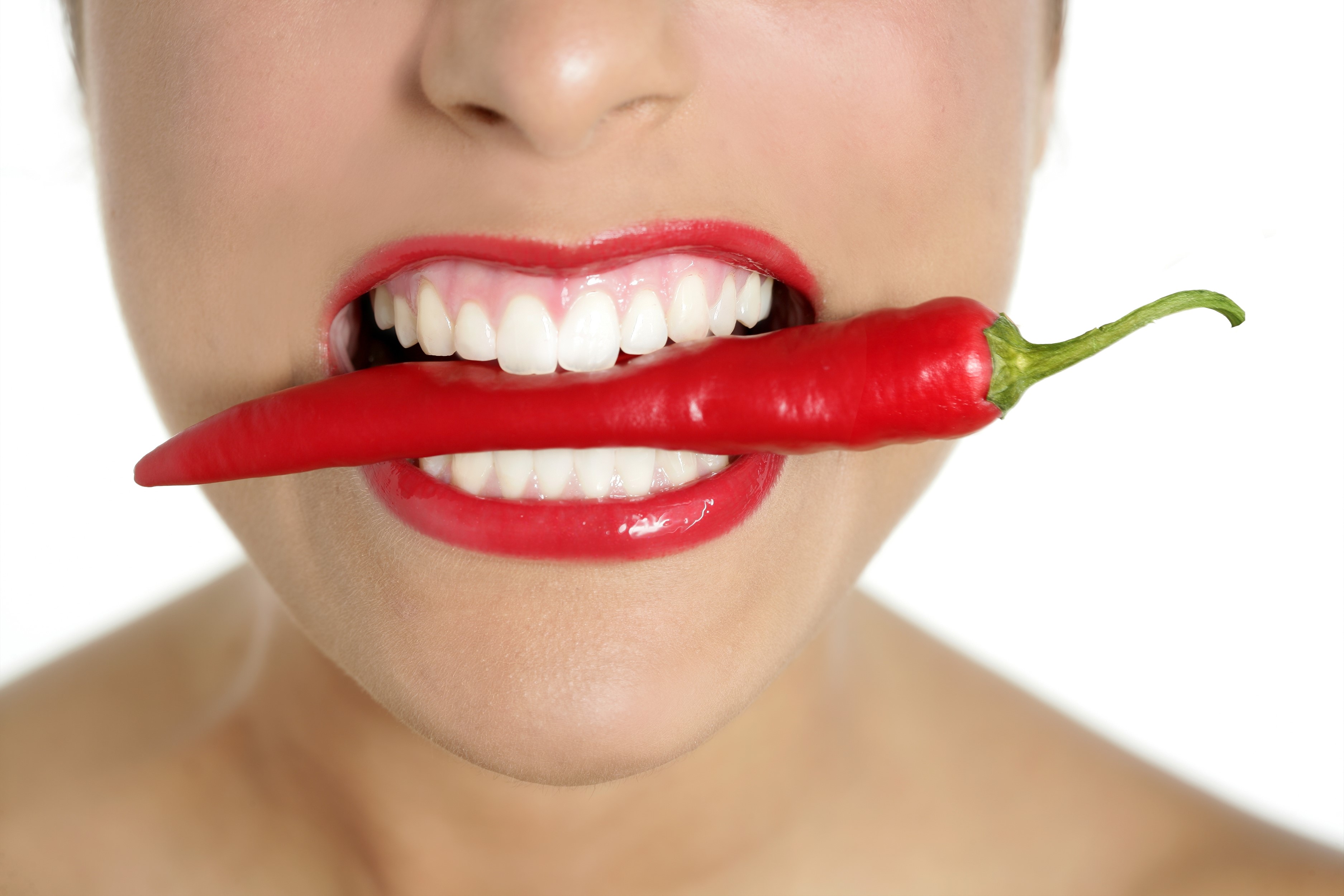 Woman biting a red chili pepper HD Wallpaper