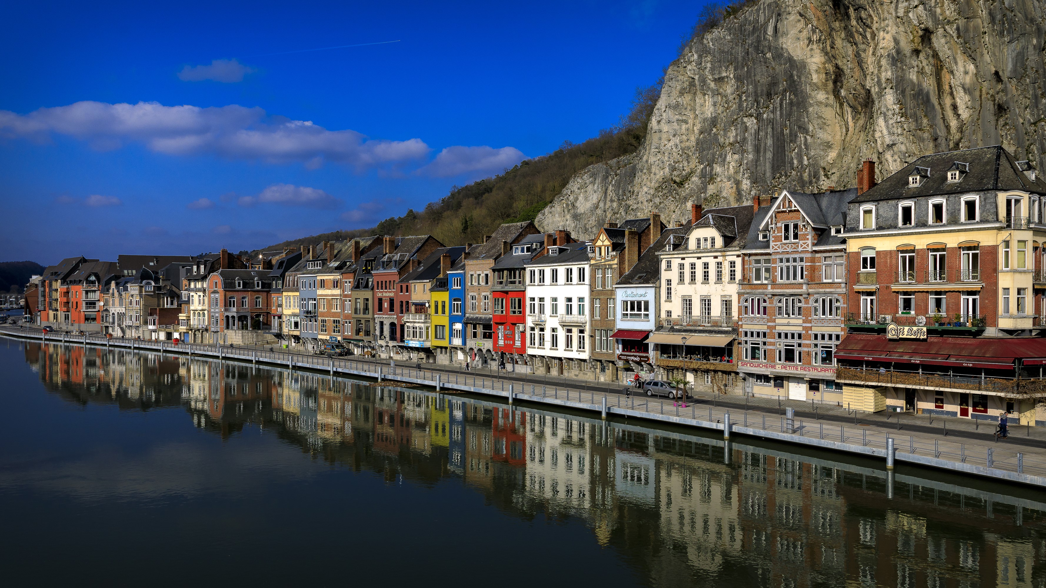 Colorful houses along the river in Dinant, Belgium with a large crag. HD Wallpaper