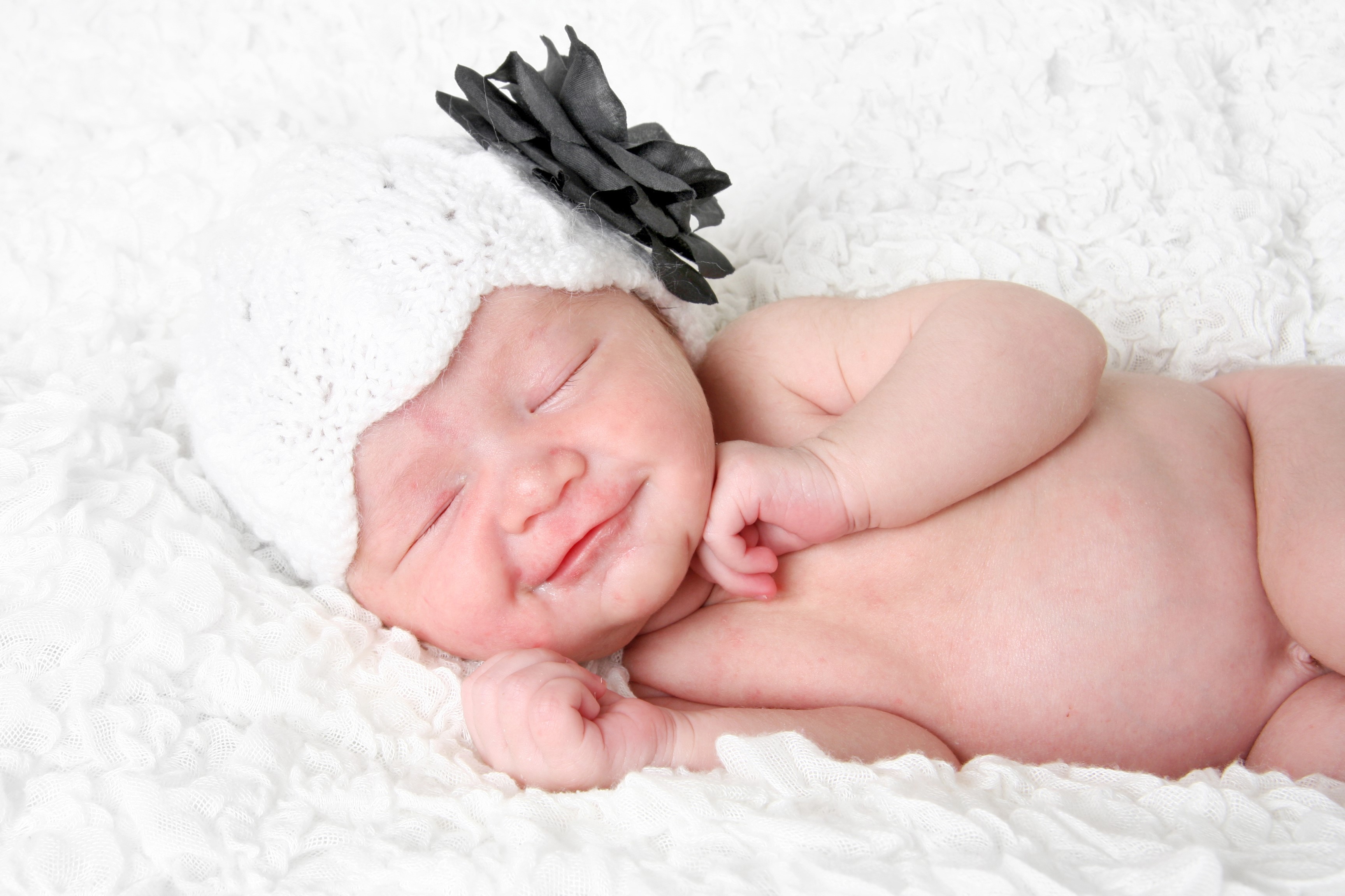 Baby wearing a white knitted hat with a black flower HD Wallpaper