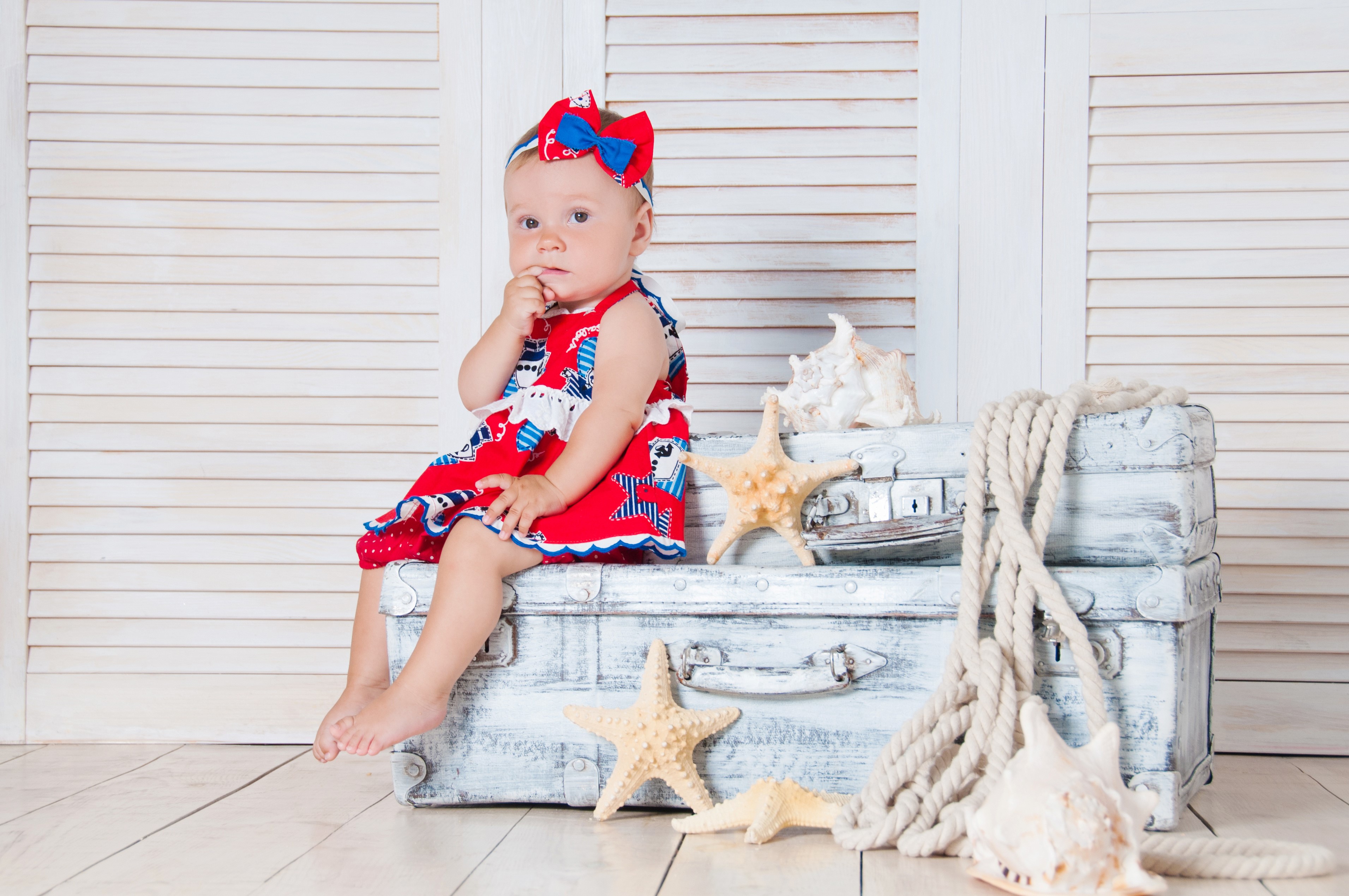 Baby girl sitting on suitcases with starfish HD Wallpaper