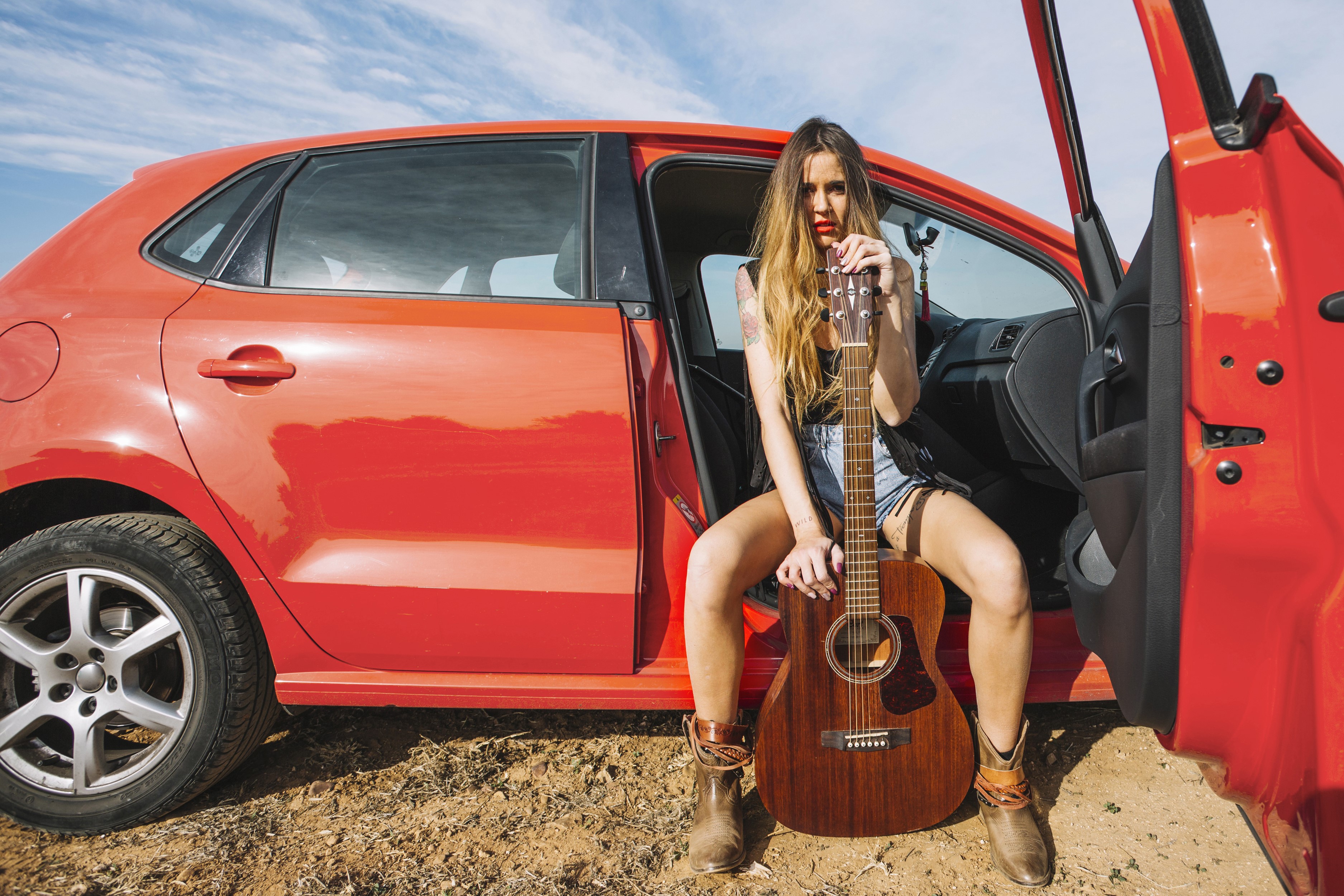 Woman with guitar sitting by a red car HD Wallpaper