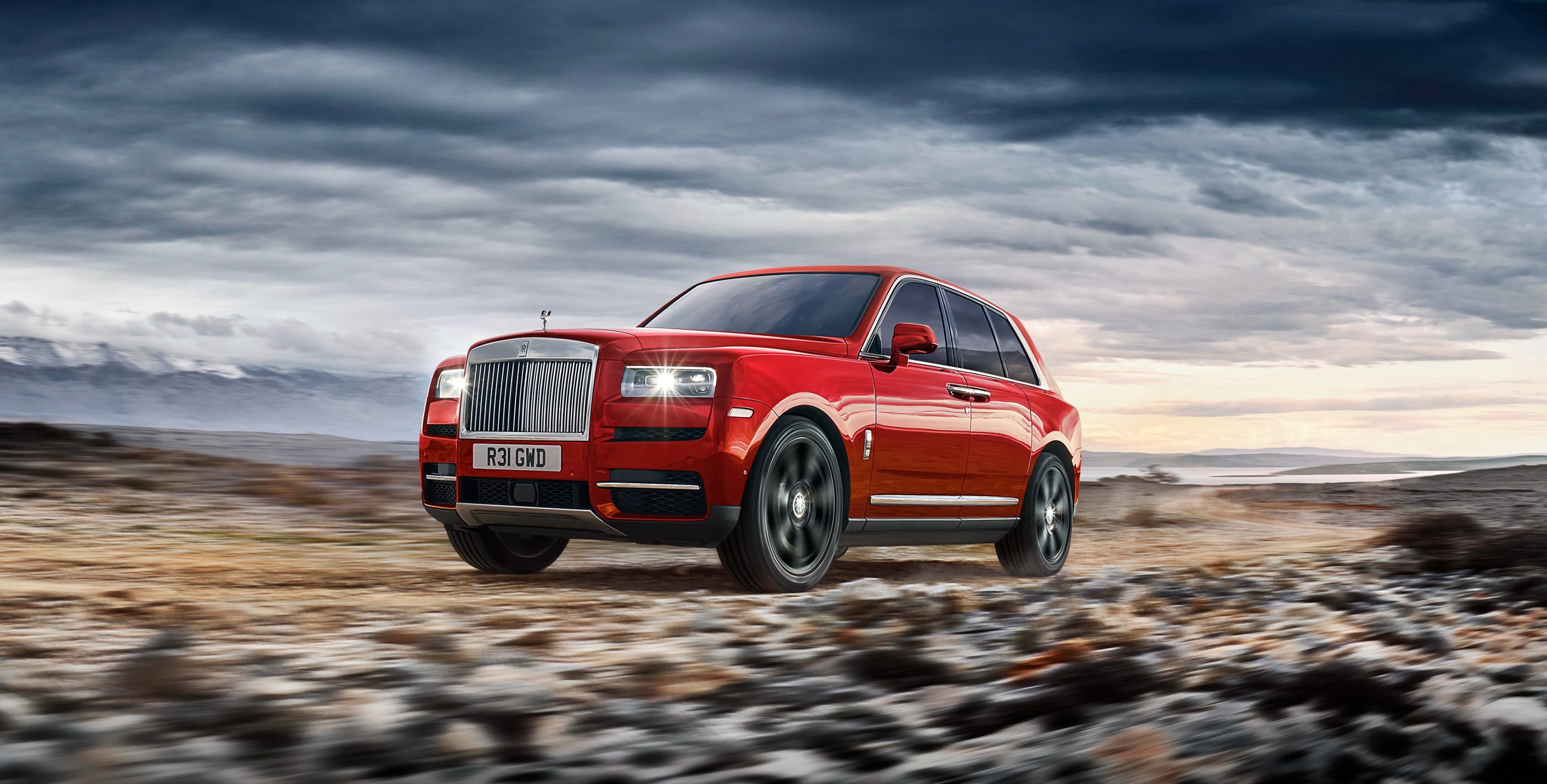Red Rolls-Royce Cullinan driving on a dirt road HD Wallpaper