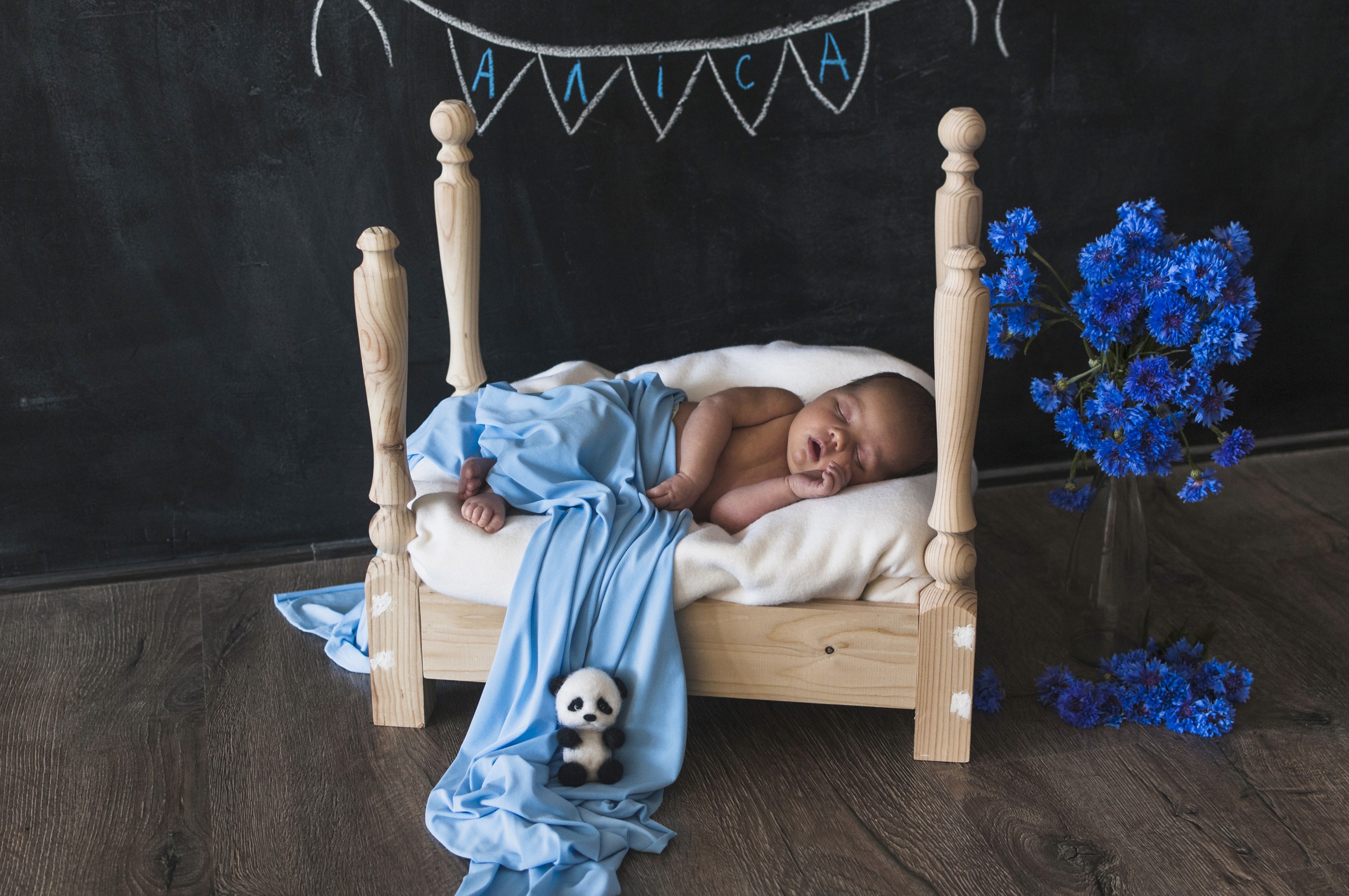 Newborn baby sleeping in a wooden bed with cornflowers HD Wallpaper