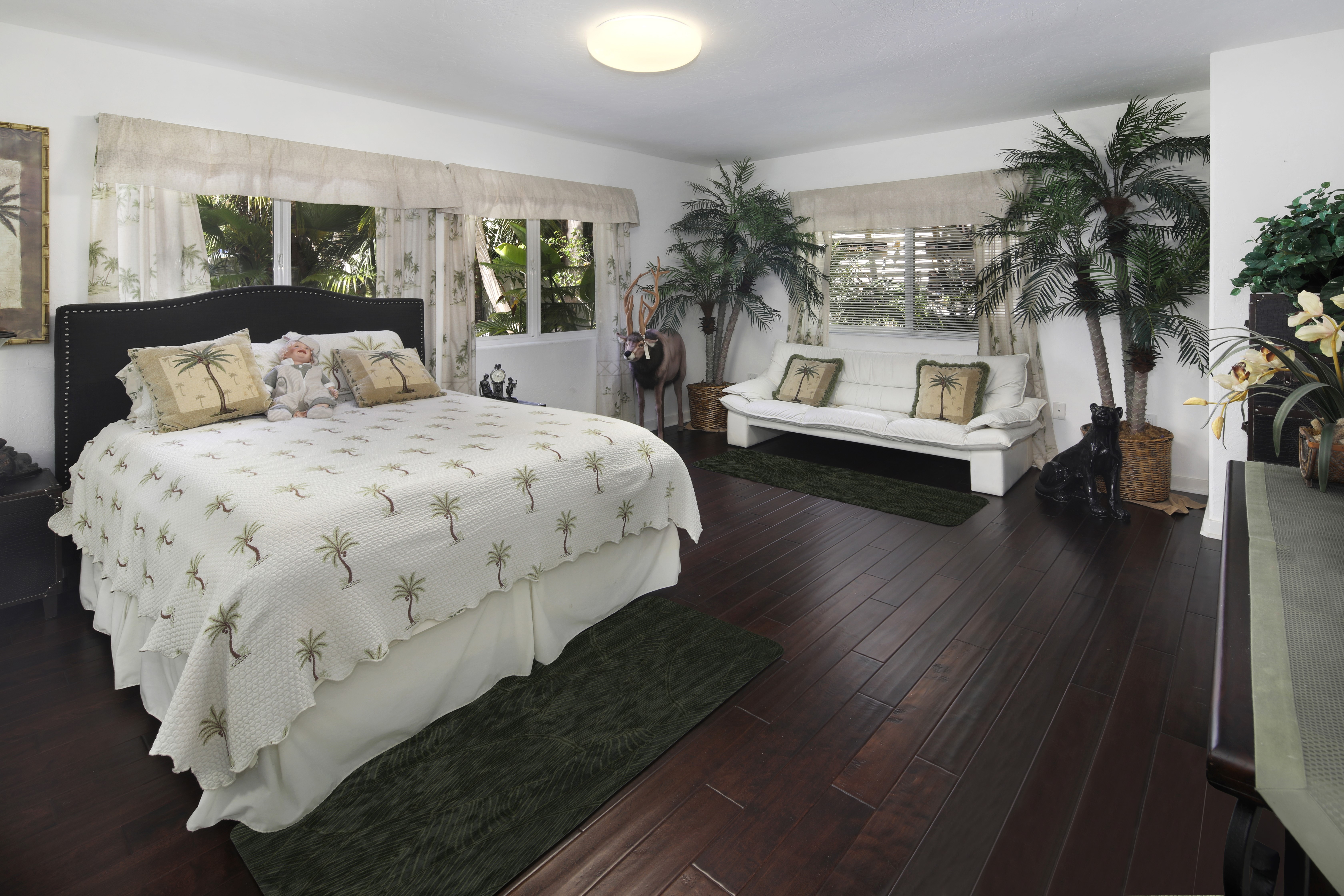 Bedroom with bed, sofa, and palm tree decor HD Wallpaper