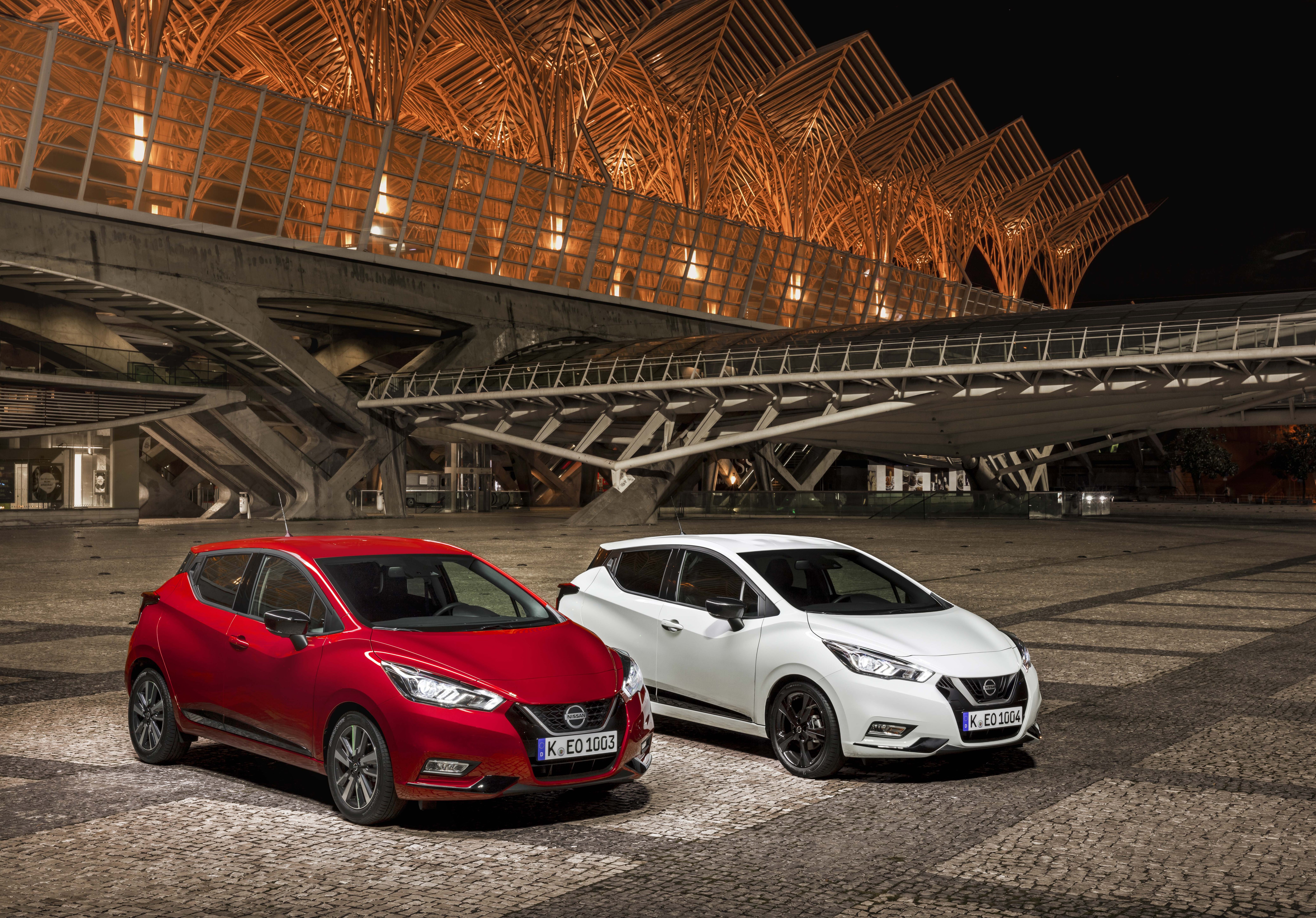 Two Nissan Micra cars in front of a modern building HD Wallpaper
