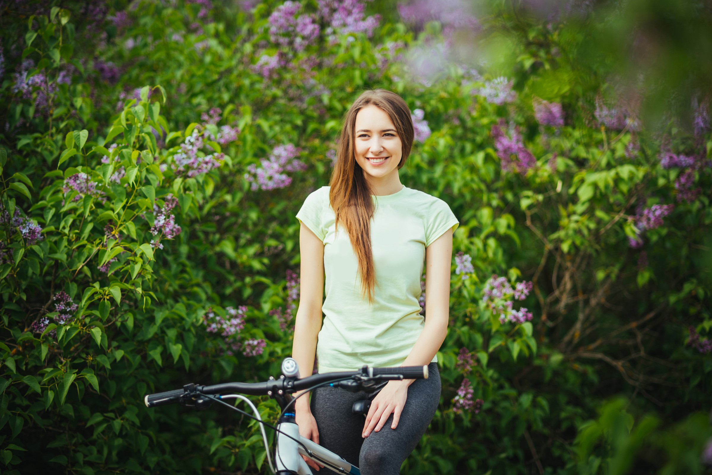 Woman with bicycle in front of lilac bush HD Wallpaper