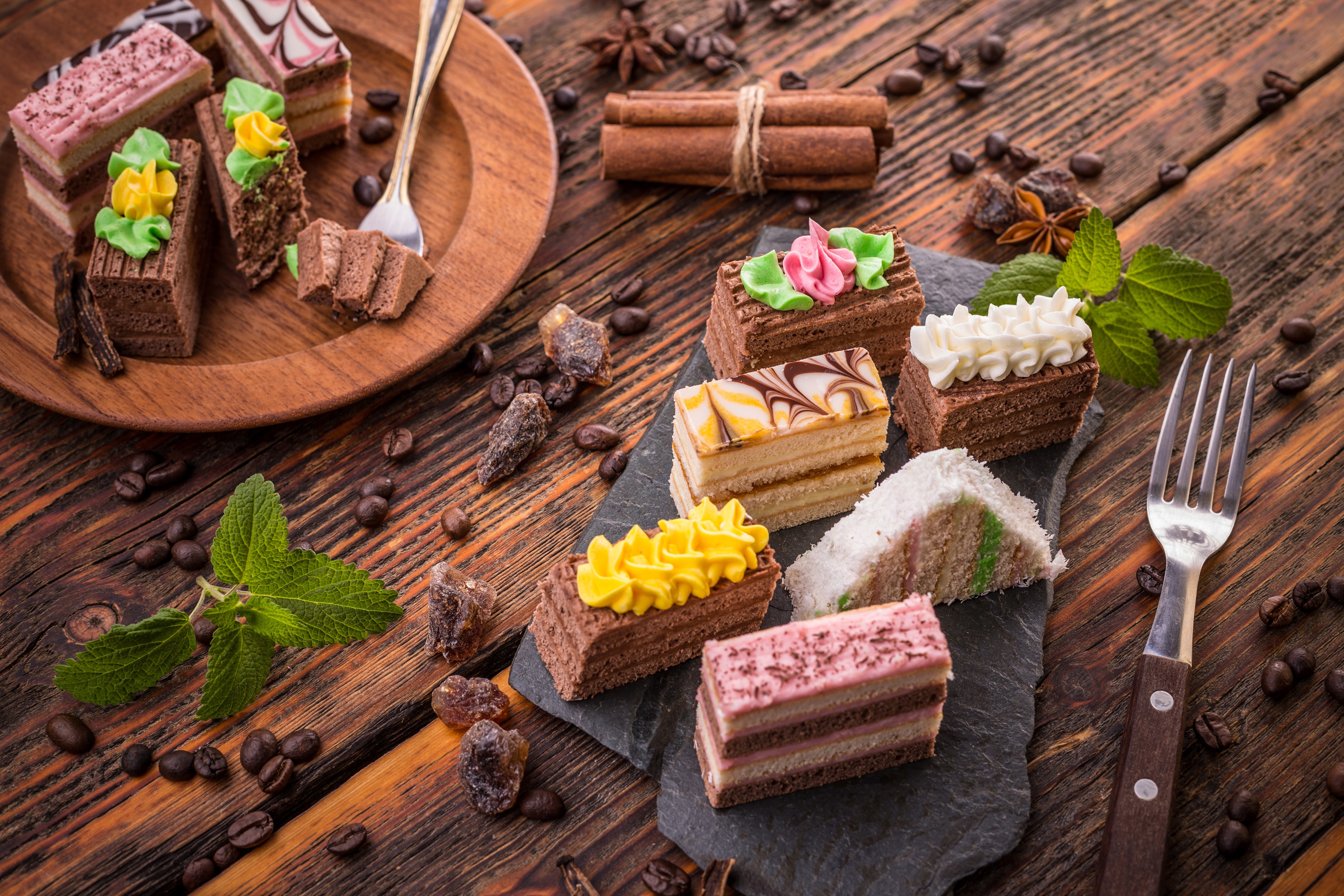 Assortment of small cakes with coffee beans and cinnamon sticks HD Wallpaper