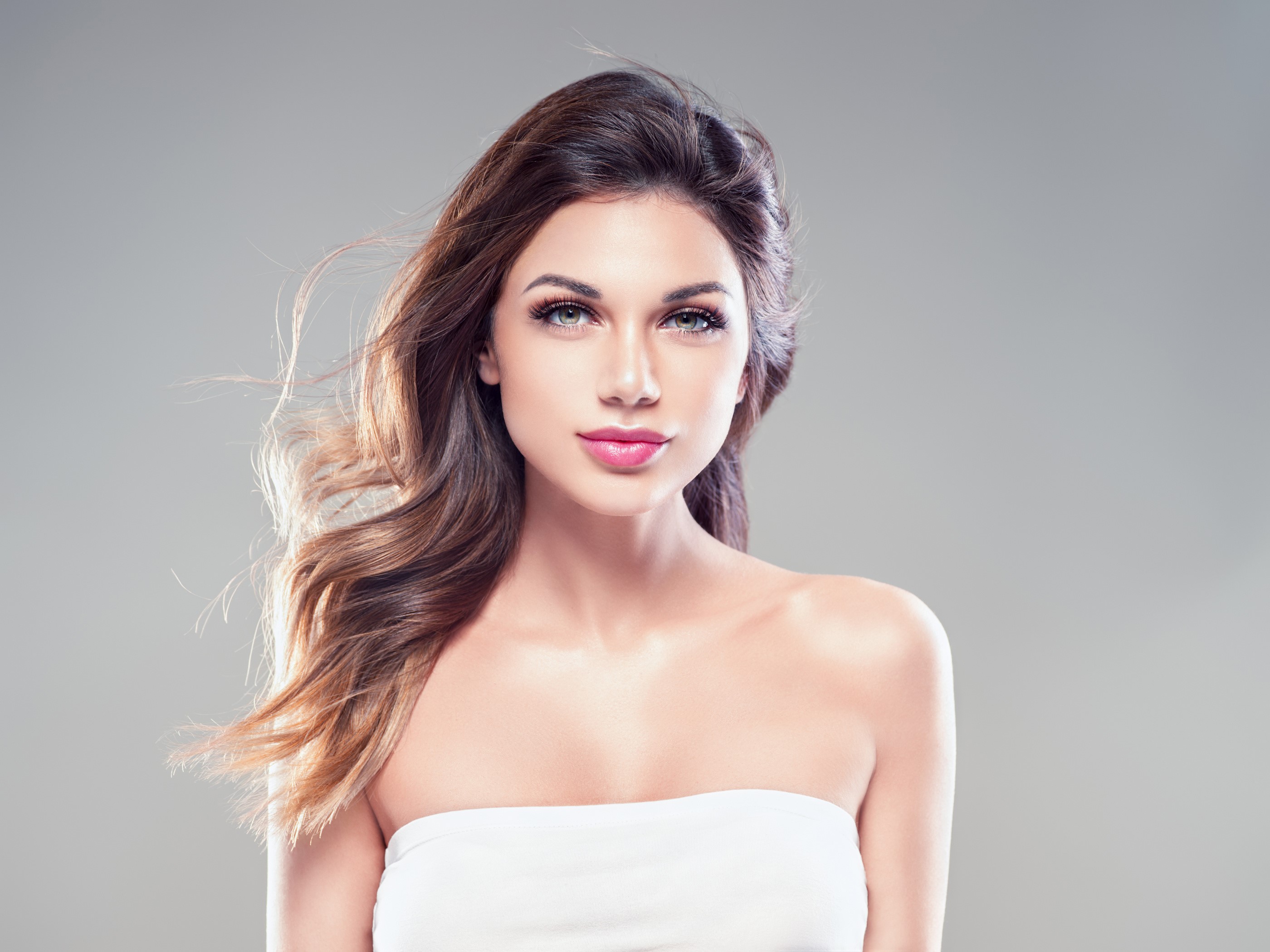 Brown haired woman with wavy hair on gray background HD Wallpaper
